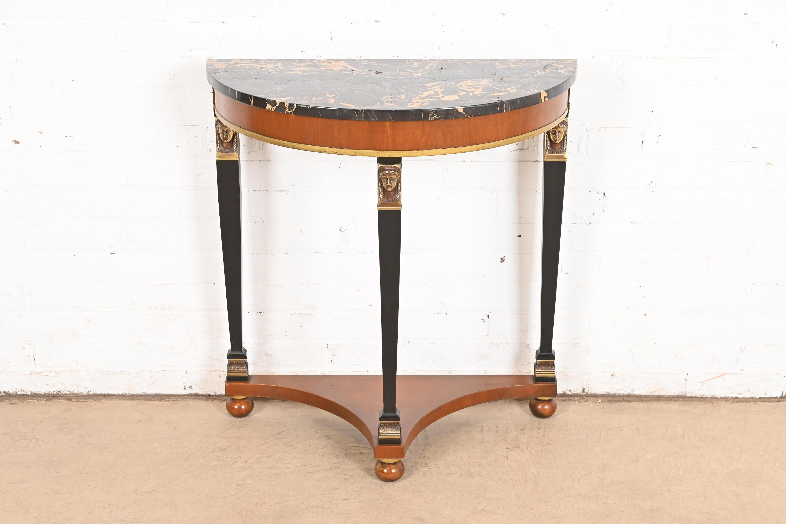 A gorgeous Empire or Neoclassical style demilune console or entry table

By Fine Arts Furniture Co. and retailed by Marshall Field & Co.

USA, Circa 1960s

Beautiful carved cherry wood, with ebonized and gold gilt trim and columns, Italian marble