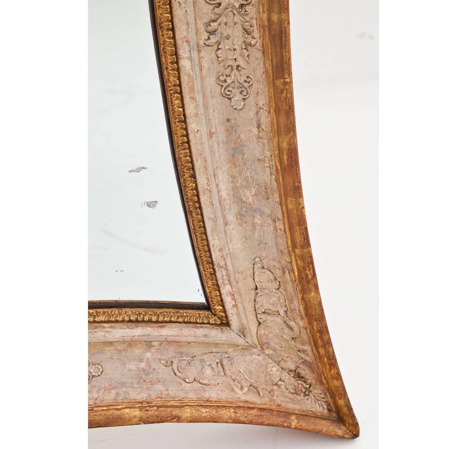 Empire mirror in a concave frame with white painted stucco décor in the typical style of the Empire. The mirror glass is secondary; the decors show some wear. 
Dimensions mirror glass in cm (H x W x D):
67 x 54.