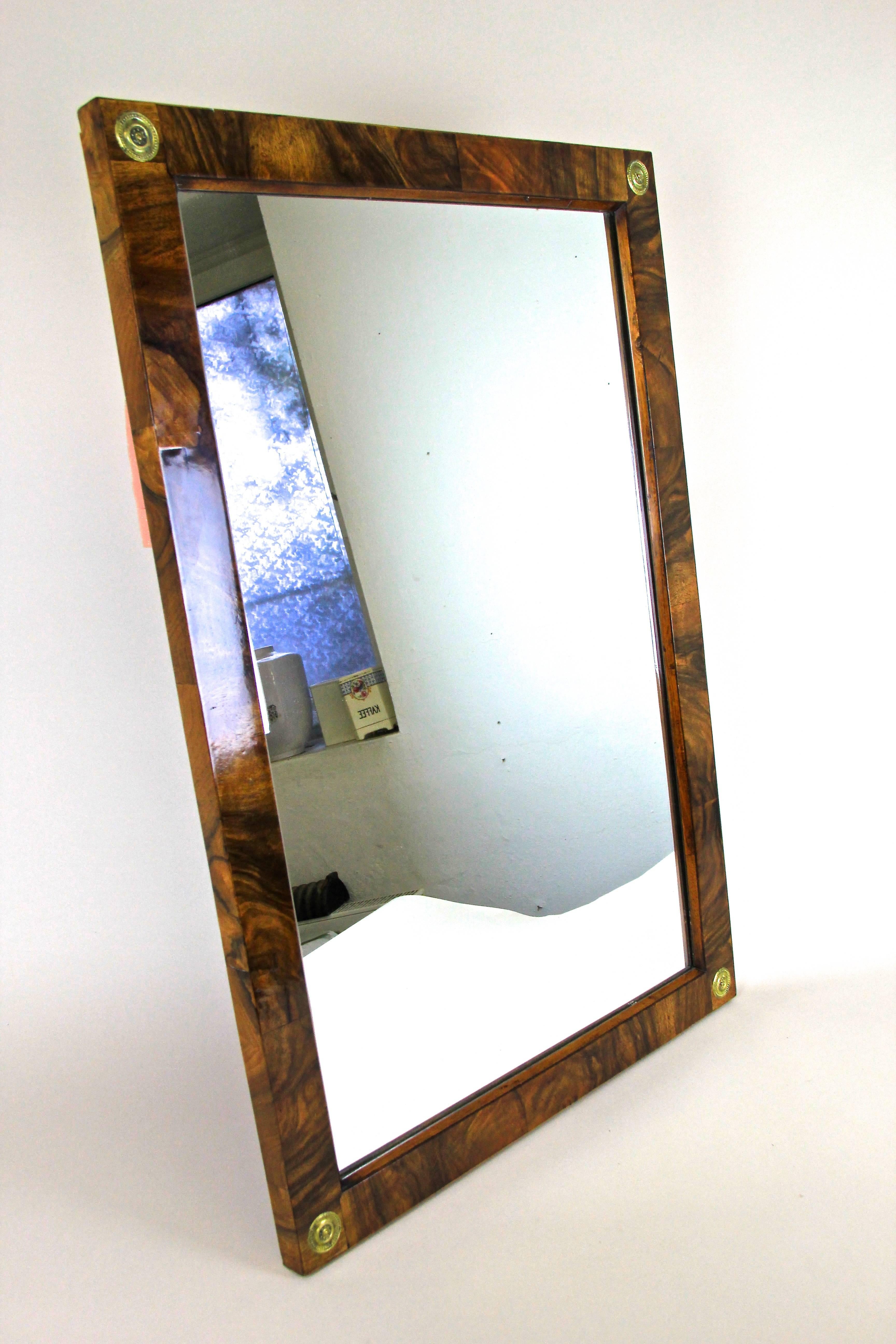 Remarkable empire nut wood wall mirror from the renowned period in Austria, circa 1815. Made with fine walnut veneer this over 205 year old mirror shows a fantastic grain and comes with a traditional shellac finish. Lovely brass rosettes adorn each