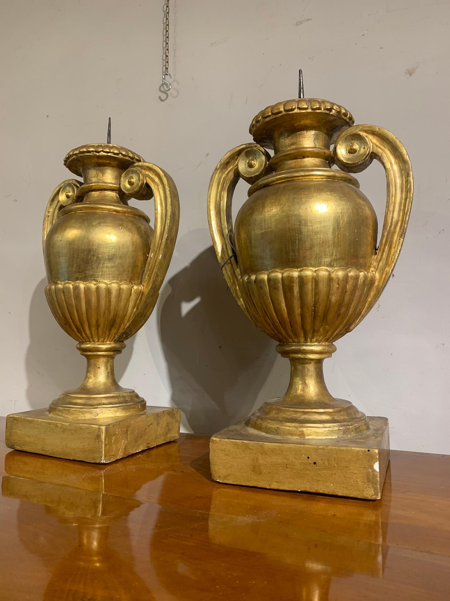 Pair of candlesticks for one light in carved pine wood and gilded with gold leaf. Classic shape of the empire style amphora with curly grips.
Centerpiece candlesticks, also suitable for creating splendid lampshades.