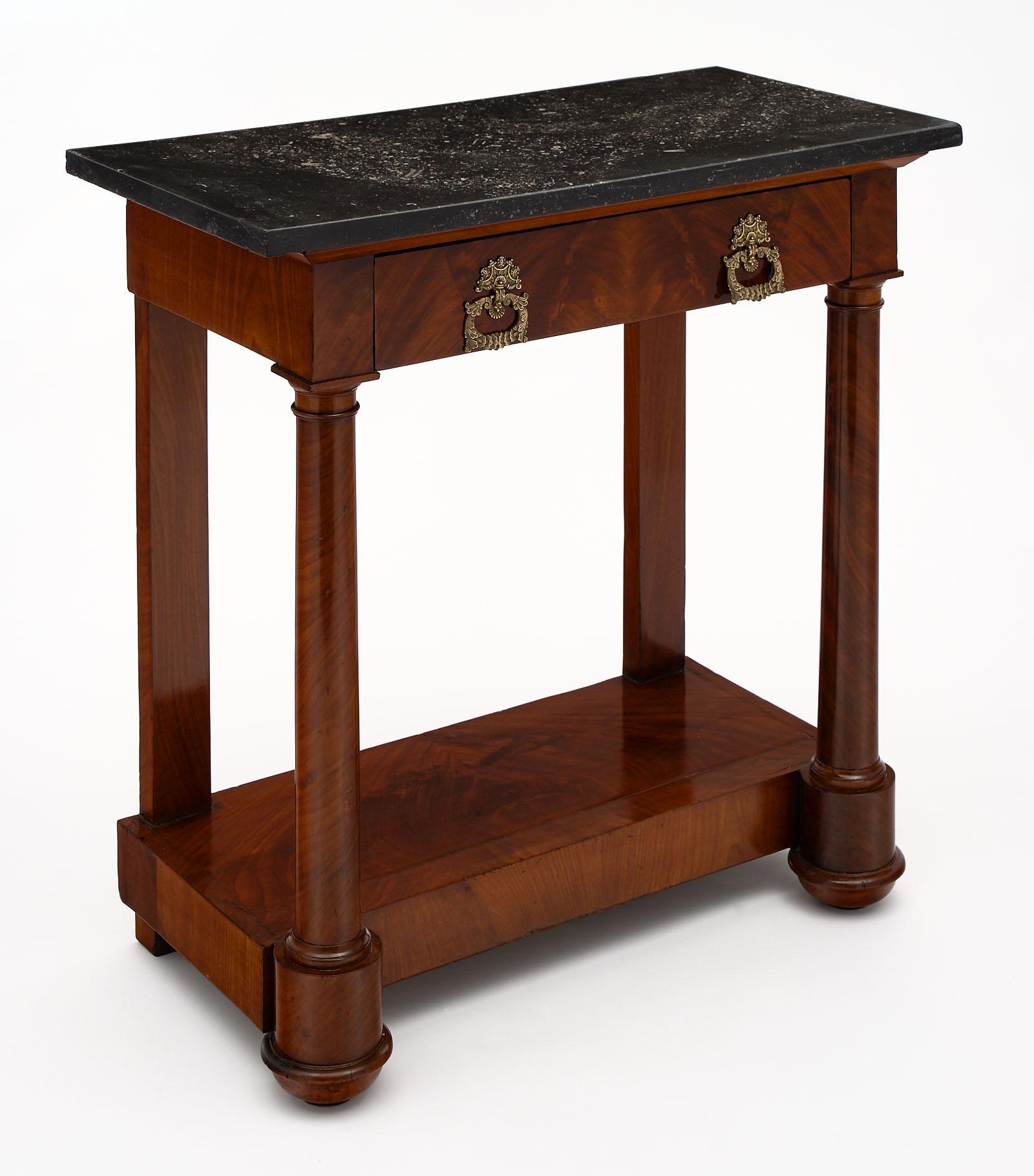 Empire period antique console table with marble top. This petite piece is made of mahogany with a black marble top. We love the finely cast bronze hardware as well!