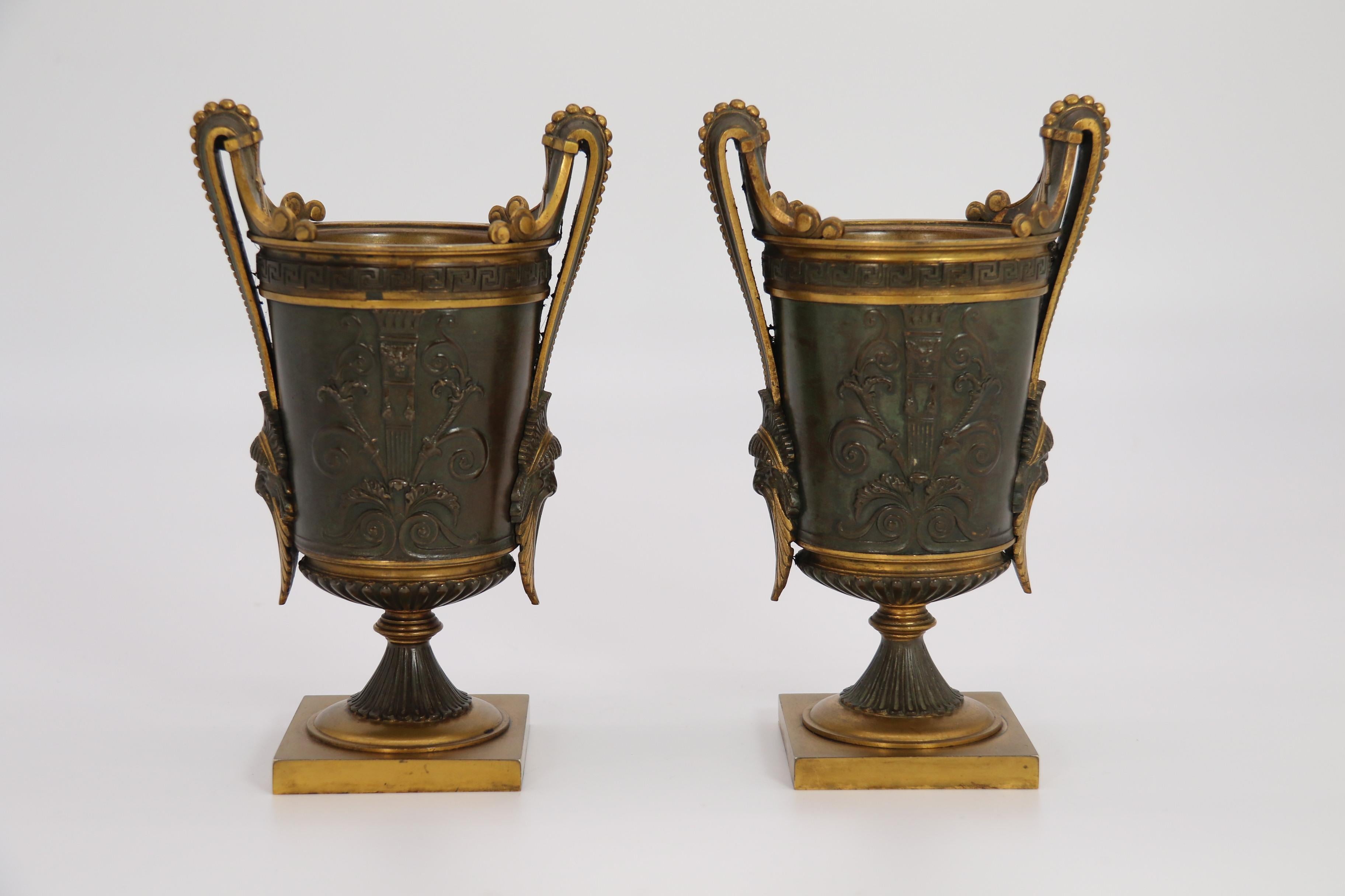 This superb quality pair of French Empire classical twin handled urns is very stylish and cast in very heavy solid bronze with alternate sections highlighted with original ormolu which is in excellent condition.

The urns stand on square plain bases