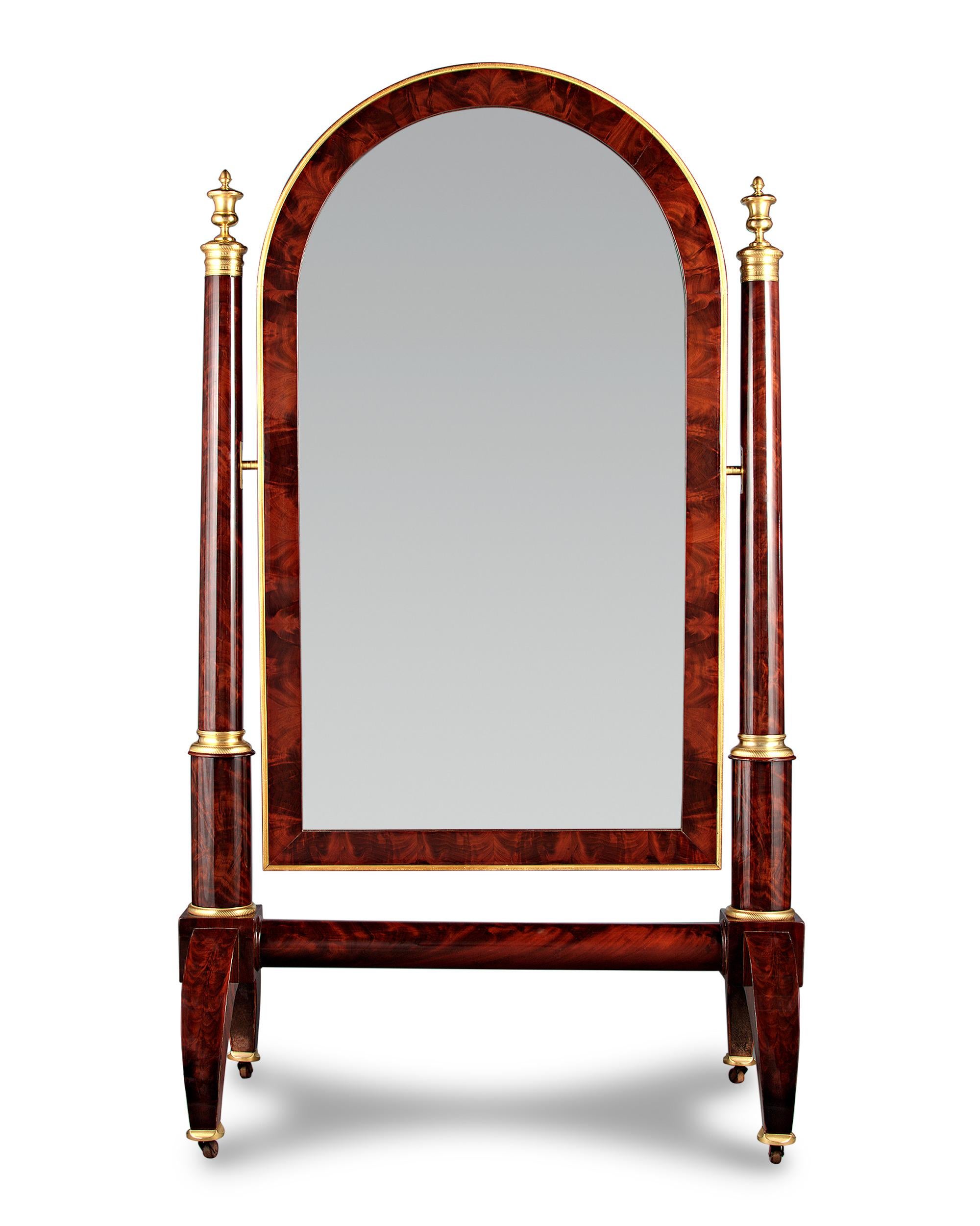 This French cheval mirror captures the luxury of the Empire period in grand style. Crafted of mahogany, the period piece is graced by intricate doré bronze mounts that embody the classically-inspired style of the Napoléonic era. Elegant urns and