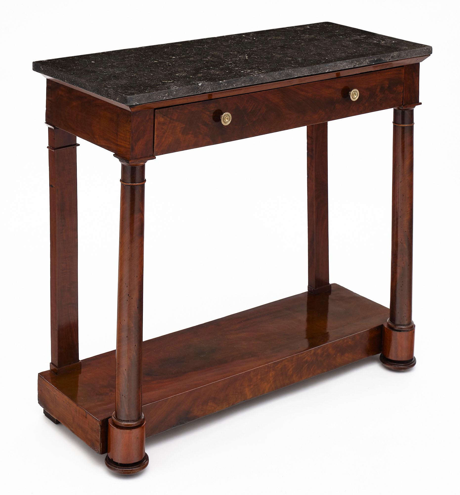 Empire period console table from France made of flamed Cuban mahogany. This piece has one dovetailed drawer with bronze hardware and a lower shelf. It is topped with a slab of gray marble.