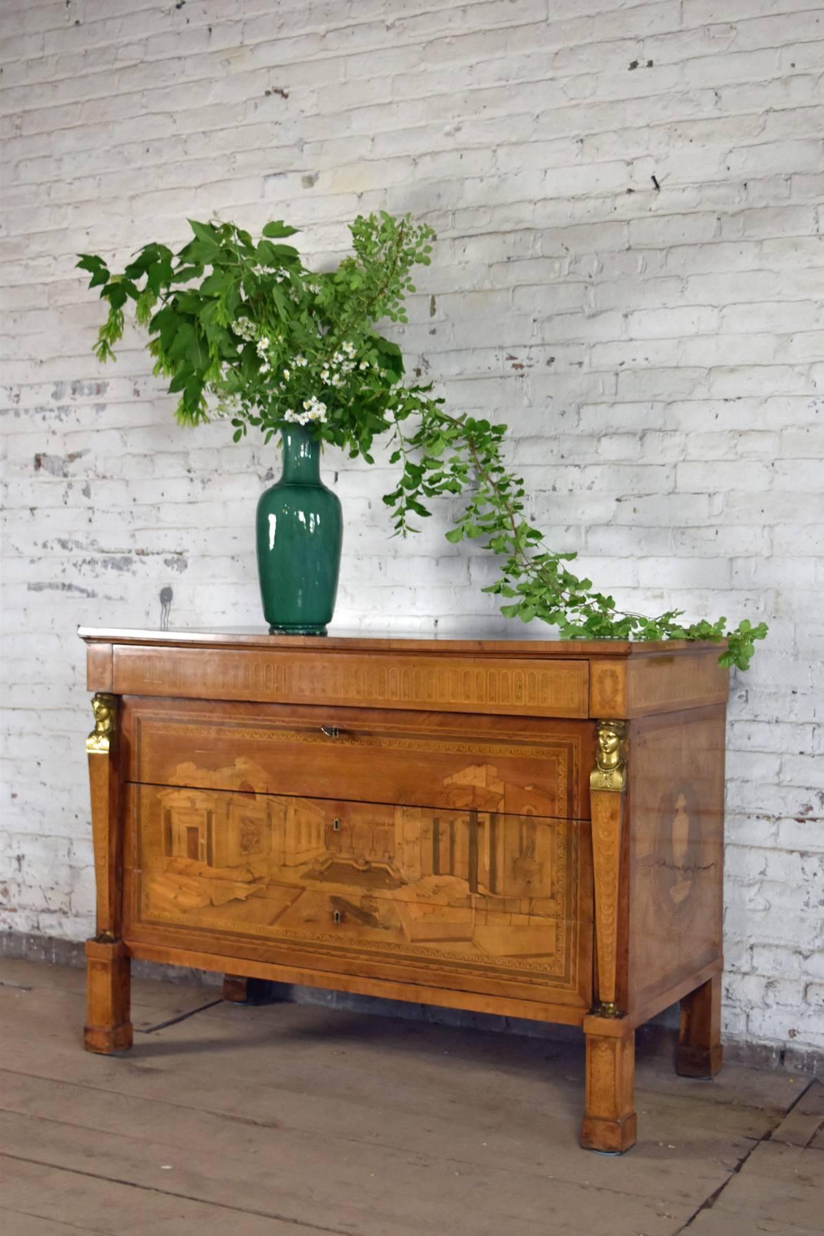 La commode de forme néoclassique rare, avec une belle couleur chaude, est un merveilleux exemple de marqueterie en perspective, dans la tradition de Giuseppe Maggiolini et de son élève Giovanni Maffezzoli ; très probablement réalisée par Tommaso