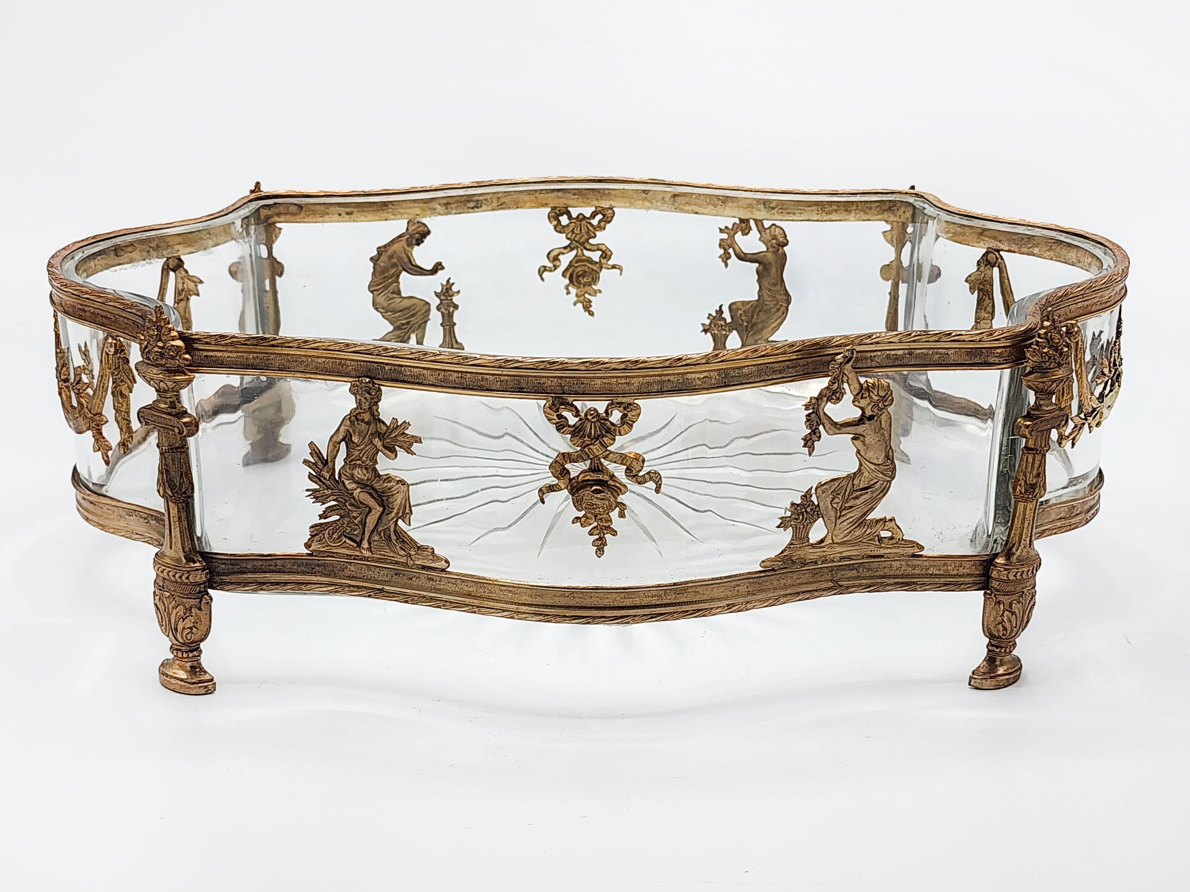 Fioriera Impero con montatura in bronzo XIX secolo
Antica fioriera in vetro tagliato con montatura in bronzo dorato con un disegno neoclassico con 4 dame, due per lato con nastri e ornamenti.
Misure:
Altezza: 10 centimetri
Lunghezza: 30