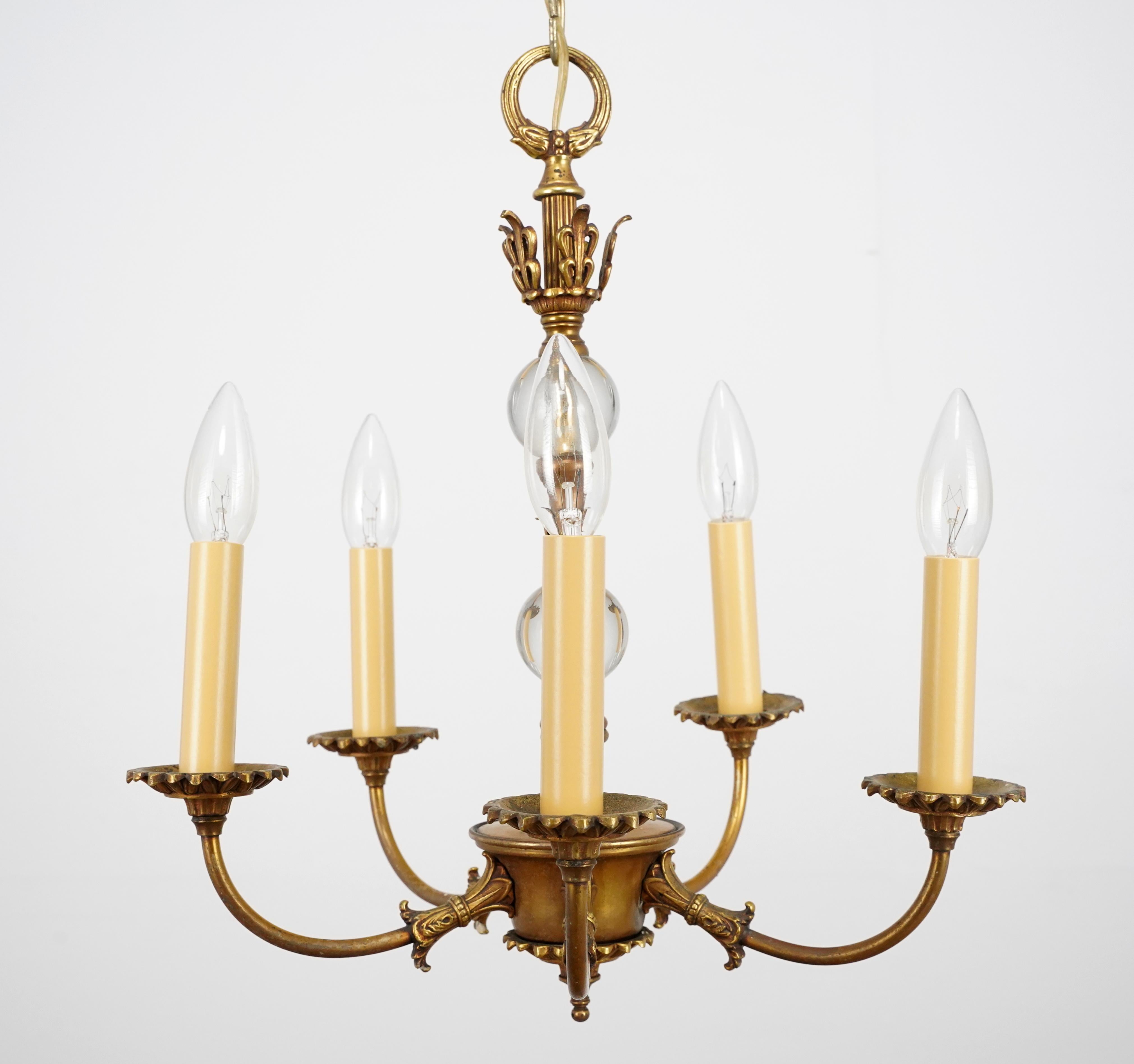 Empire Revival style chandelier made of bronze with clear glass central accents. This light requires five E-12 candelabra light bulbs. The chain is made of steel. Cleaned and restored. Good condition with appropriate wear from age. One available.