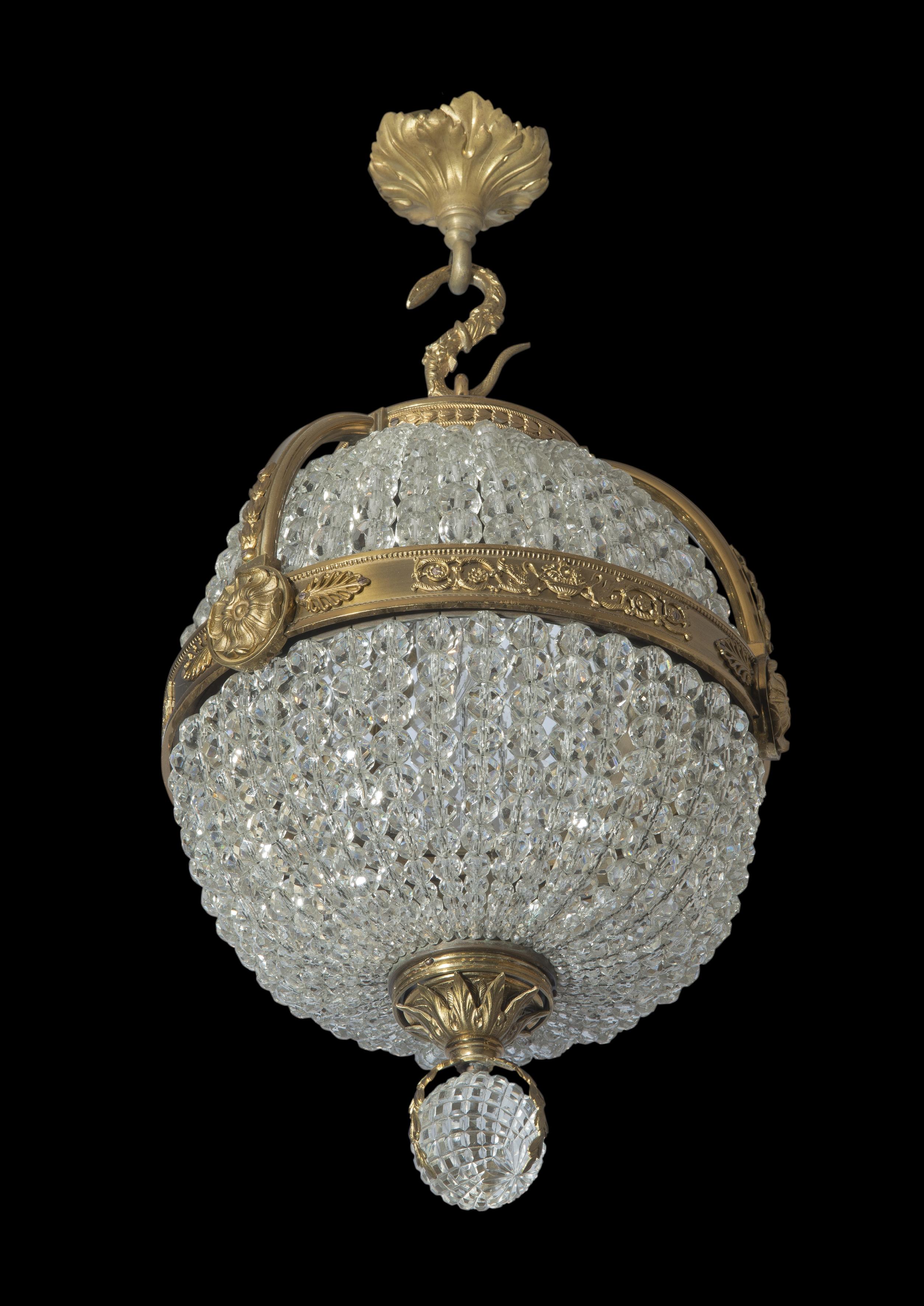 An Empire Revival gilt-bronze and cut-glass pendant chandelier.

French, circa 1910. 

Of globular form this fine chandelier has a central gilt-bronze band cast with vases issuing flowers flanked by swan motifs and foliate bosses flanked by