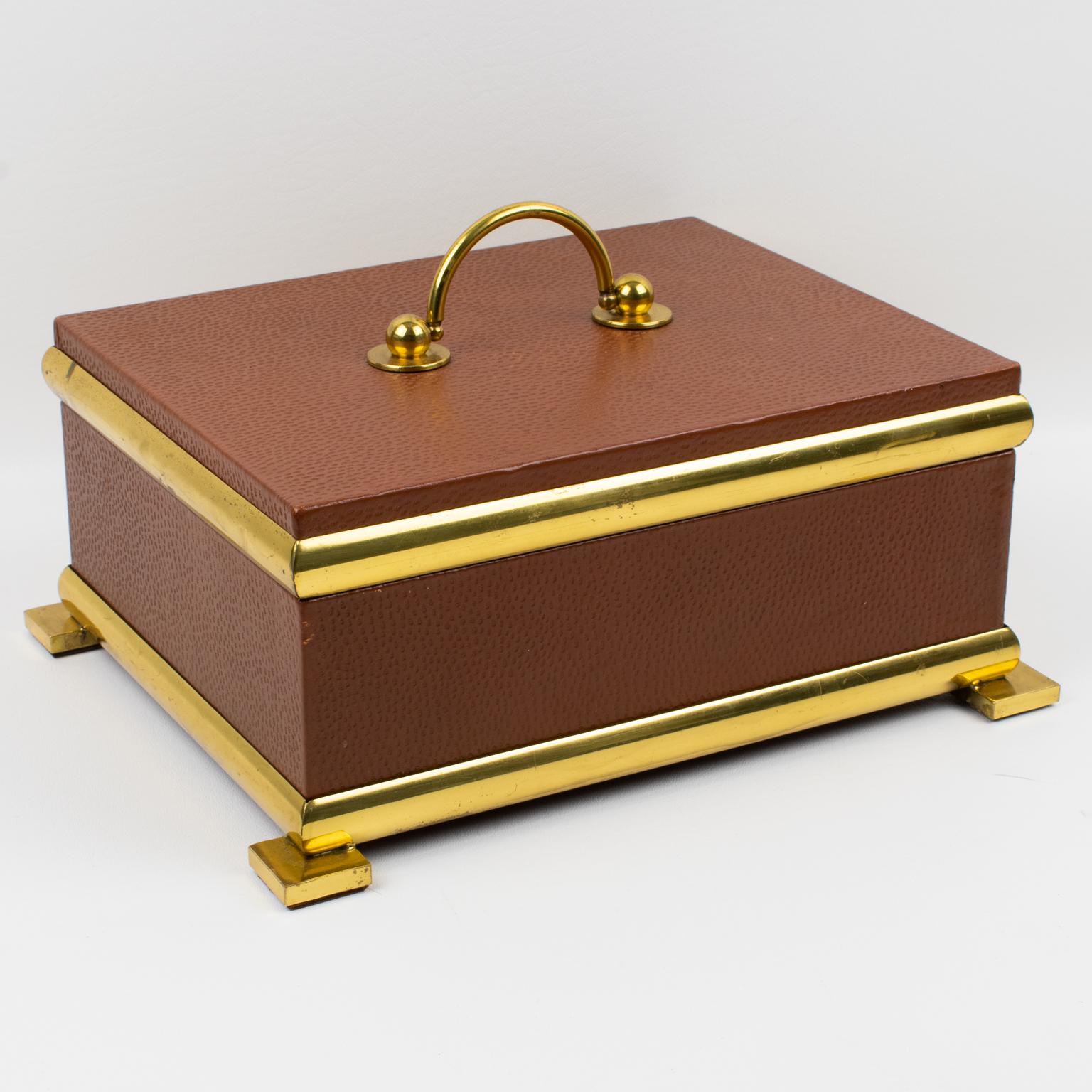 Cette élégante boîte à couvercle décorative italienne des années 1950 présente un style Empire. La forme rectangulaire haute arbore un design moderniste classique, avec un encadrement en métal laiton doré sur un corps en bois enveloppé de cuir brun