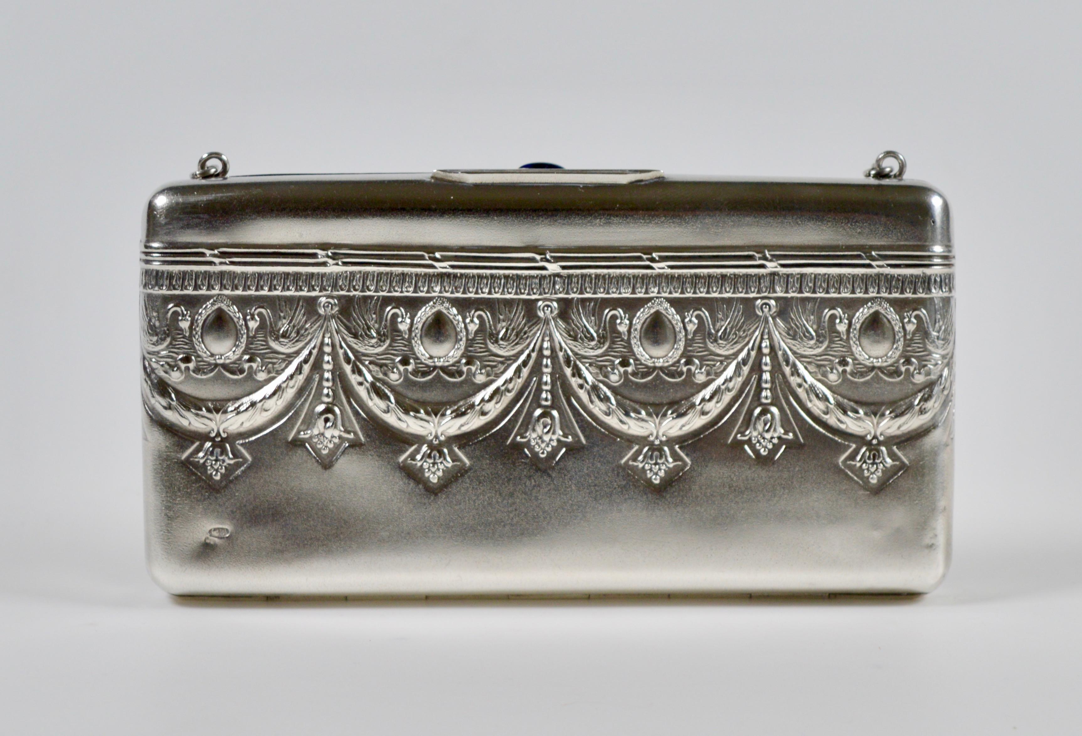 An empire revival Russian silver evening bag dating from the second half of the reign of Tsar Nicolas II. 
Beautifully decorated across the front with finely pressed swans, laural swags, ribbons and descending stylised flowers. Featuring a pushdown