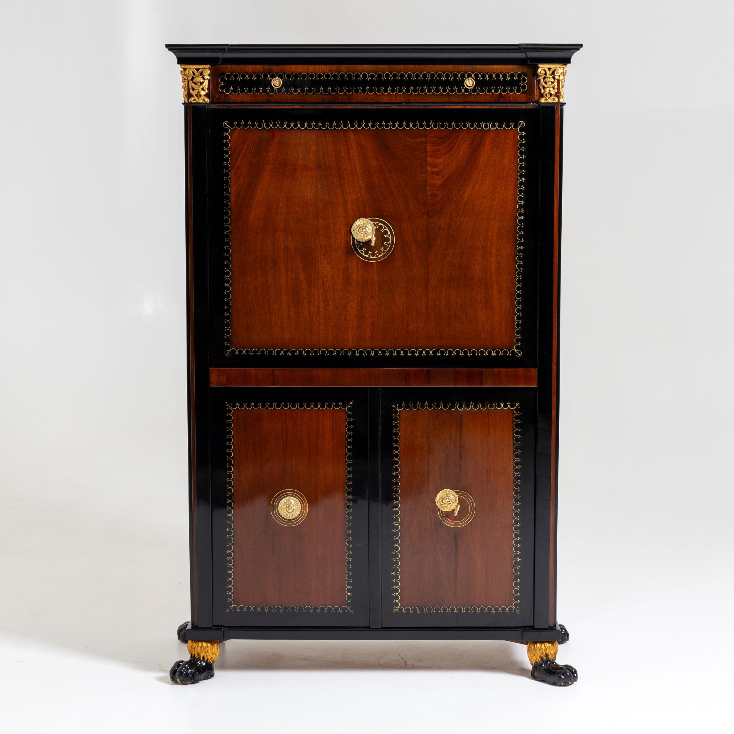 Exceptional Viennese Empire secrétaire with a classically structured design: two lower doors, a flat drop-front writing surface, and a wide drawer at the top. The piece stands on ebonized and gilt lion’s paw feet. The corners are framed by flat,