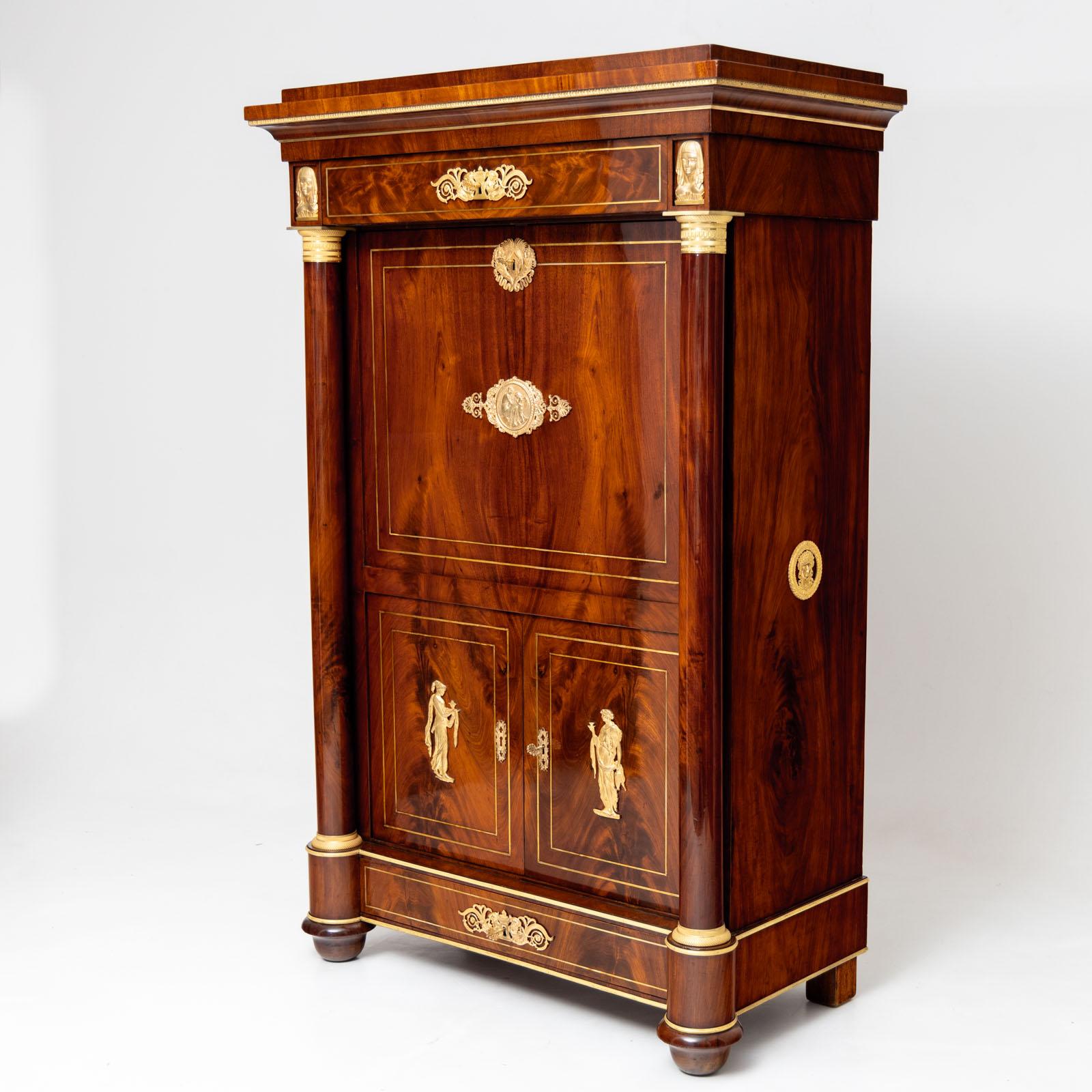 French Empire secretary à abattant with a two-door base, two wide drawers and a flat writing flap surrounded by smooth full columns with fire-gilt bronze capitals and bases. The bureau is veneered in mahogany and elegantly accentuated by fine
