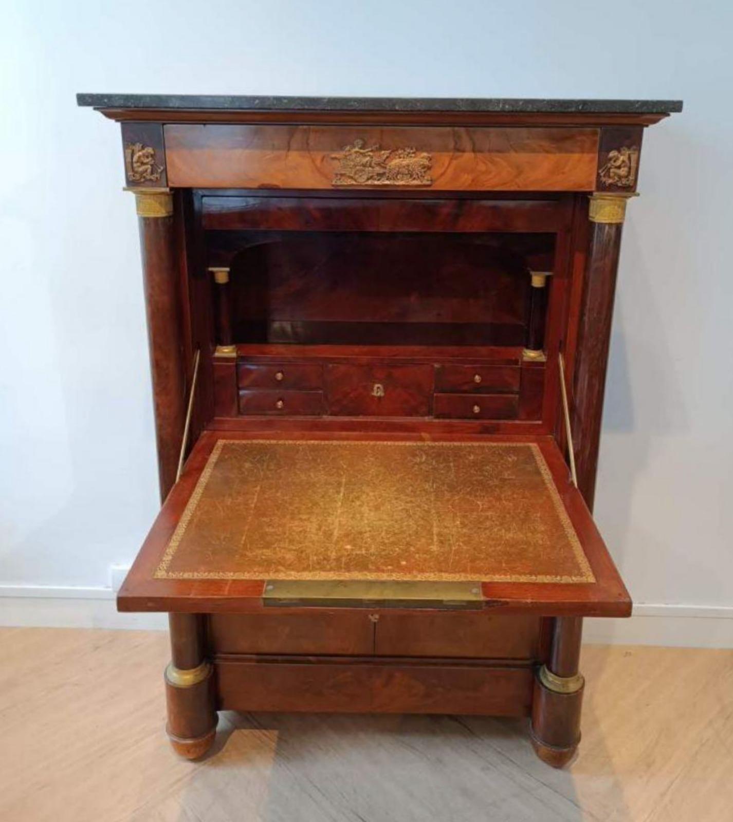 Secrétaire Empire Napoléon III 19ème siècle
ouverture avec un rabat et deux feuilles 
Montants en forme de colonnes claires 
Ornementation en bronze ciselé avec motifs de chars et de putti 
Placage d'acajou flammé, plateau en marbre noir 
H. 143 cm