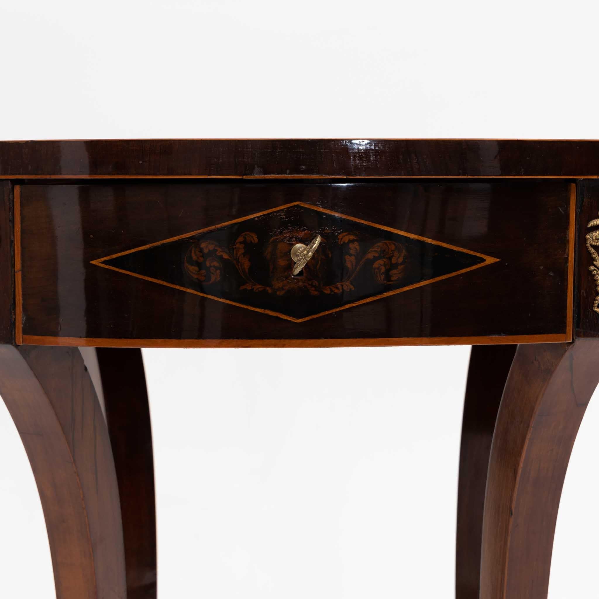 Empire sewing table with socketed saber legs and a basket tray, adorned with an oval frame featuring fire-gilded fittings. The table includes a lockable drawer with diamond-shaped fields, embellished with vine-shaped inlays and delicate ink painting.