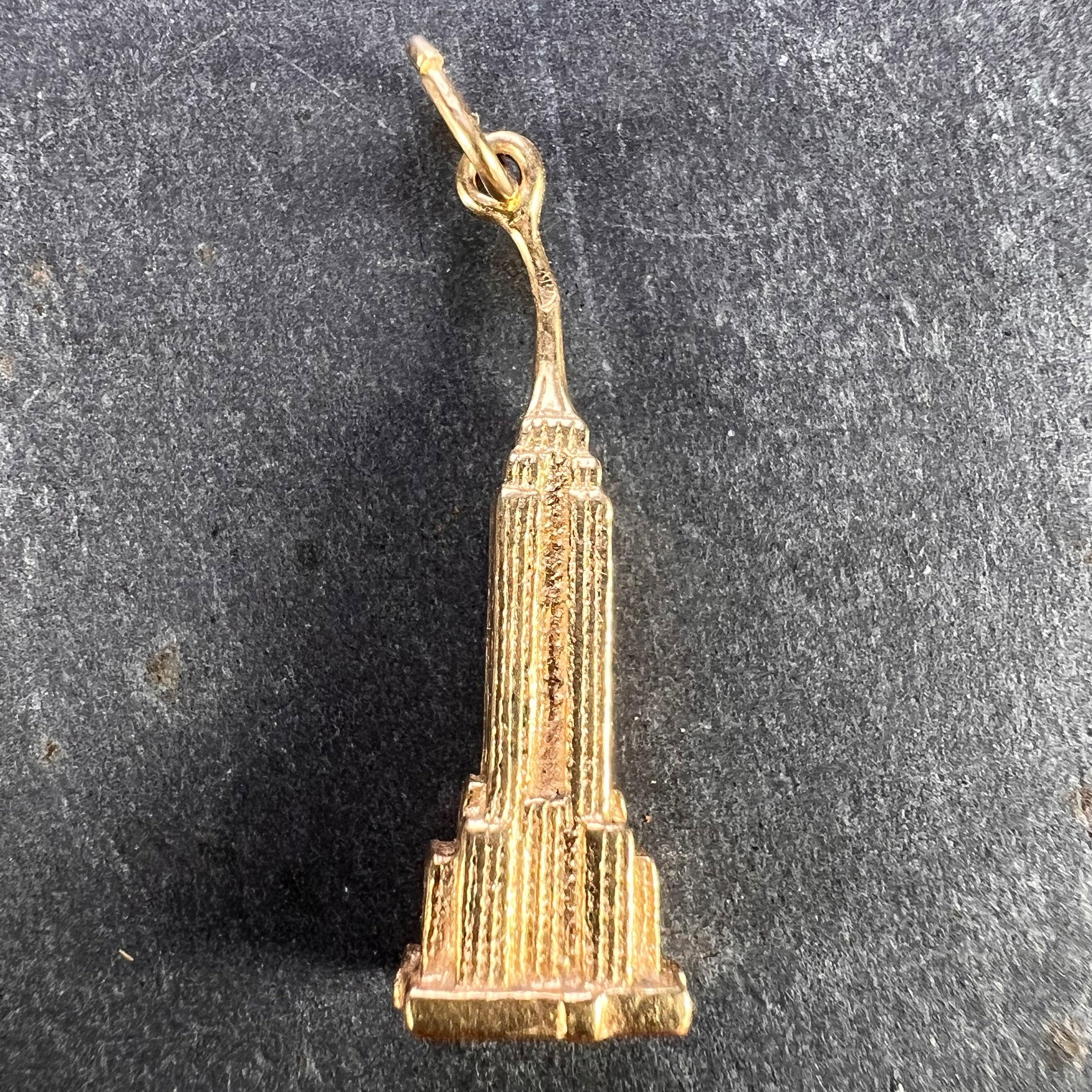 Un ciondolo charme in oro giallo 14 carati (14K) disegnato come l'Empire State Building di New York. Timbro 14K alla base del charm.

Misure: 2,7 x 0,85 x 0,6 cm (escluso l'anello di sospensione)
Peso: 3.34 grammi
(Catena non inclusa)