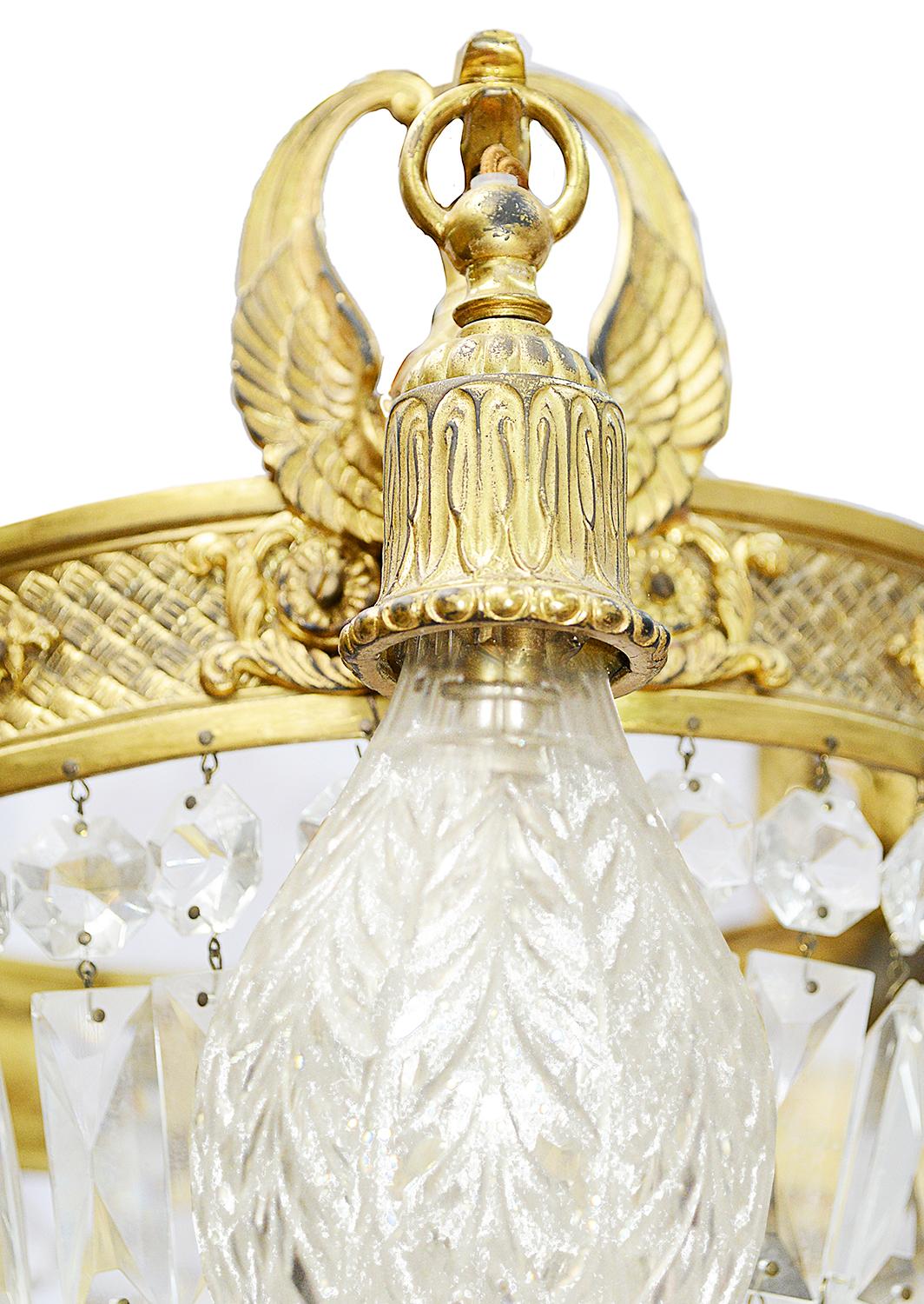 A very stylish 19th century French Empire influenced chandelier. Having feather plums to the top, chain links supporting the circular frame with cut-glass pendant basket beneath, three ormolu bell shaped bulb holders supported by mythical fish and