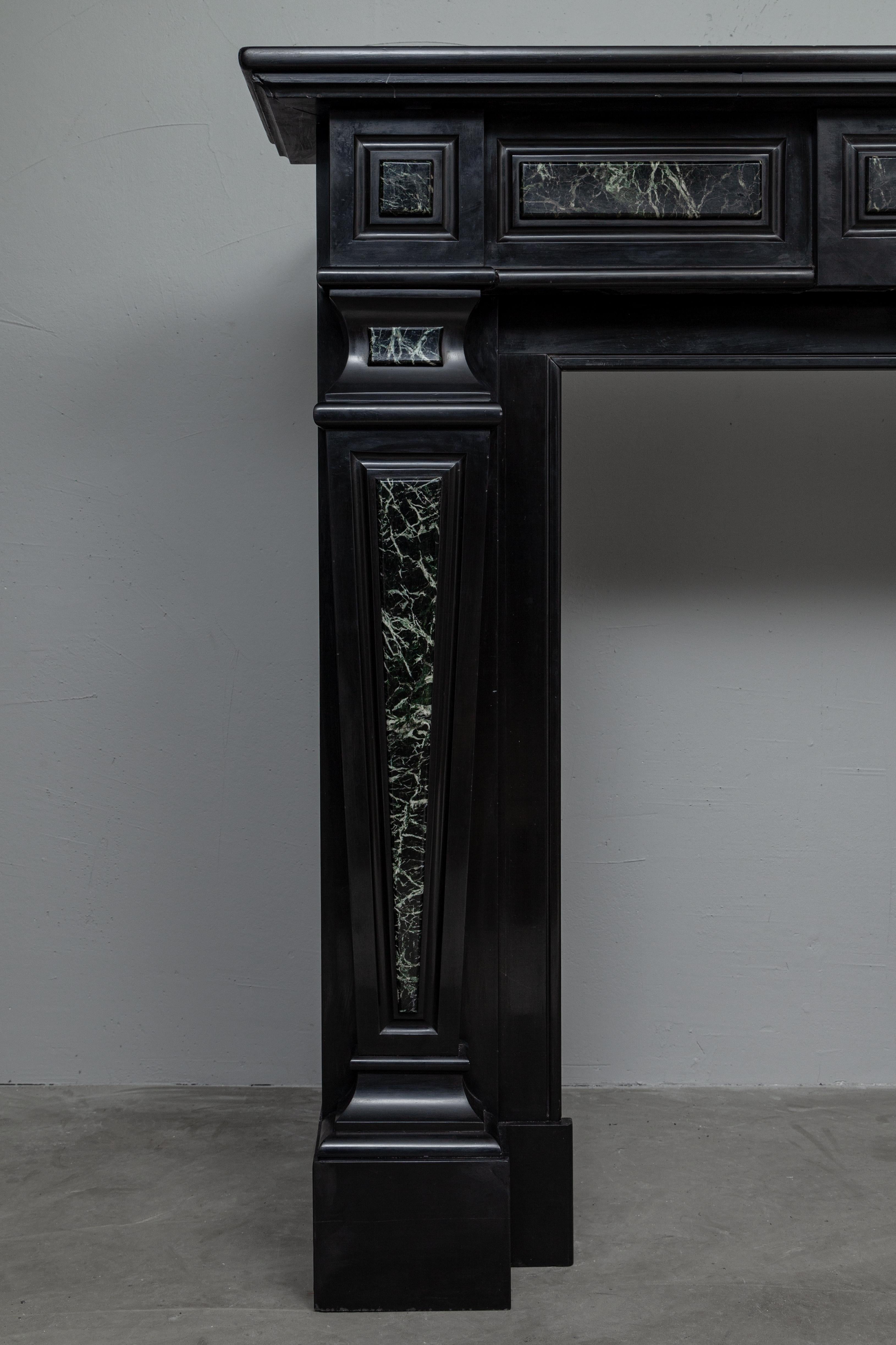 Empire-style black marble fireplace.
This extraordinary fireplace is made of Noir de Mazy marble, complemented by the luxurious green marble type Verde. Despite the clean lines, this is a very elegant piece. The richly executed consoles are a true