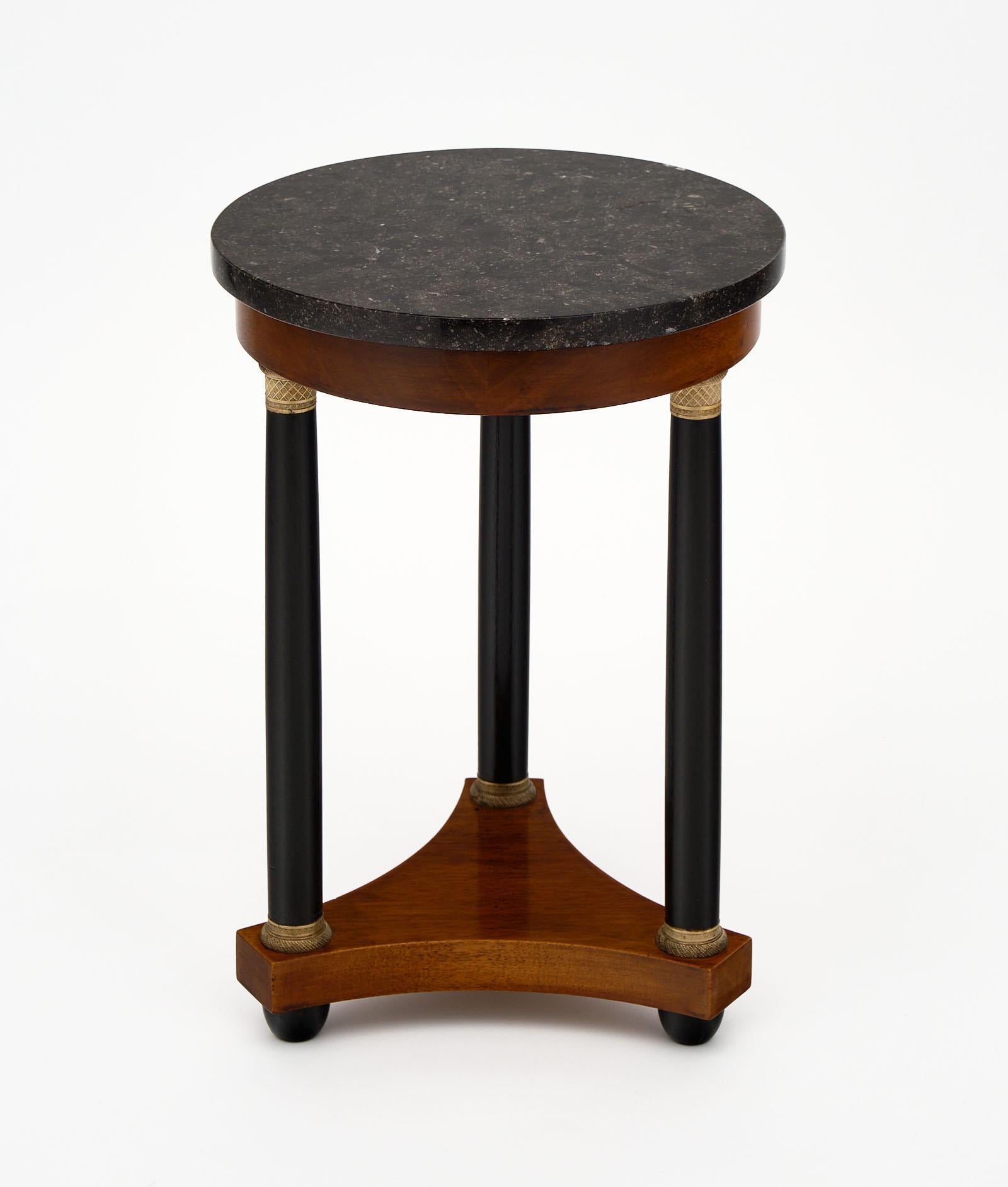 French Empire style antique side table with a mahogany tripod base. The three legs have been ebonized for added elegance. The top is an original black marble. We love the finely cast bronze elements as well!