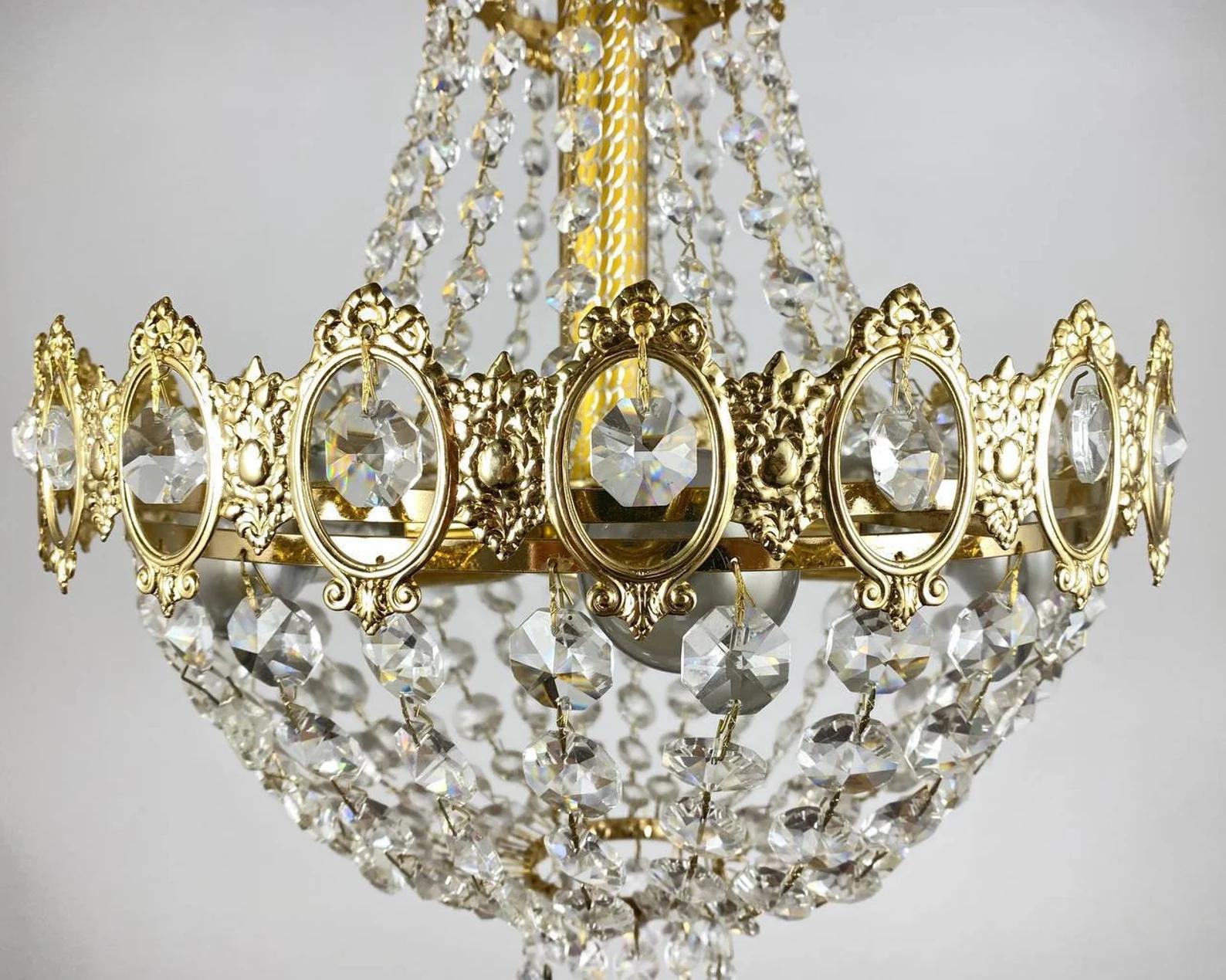 Empire style glass chandelier features 6 lights and framework with a golden iron.

Made in Belgium. 1970s.

This chandelier is lavishly draped in fine quality sparkle transparent glass cut facets.

Surprisingly elegant and memorable ceiling