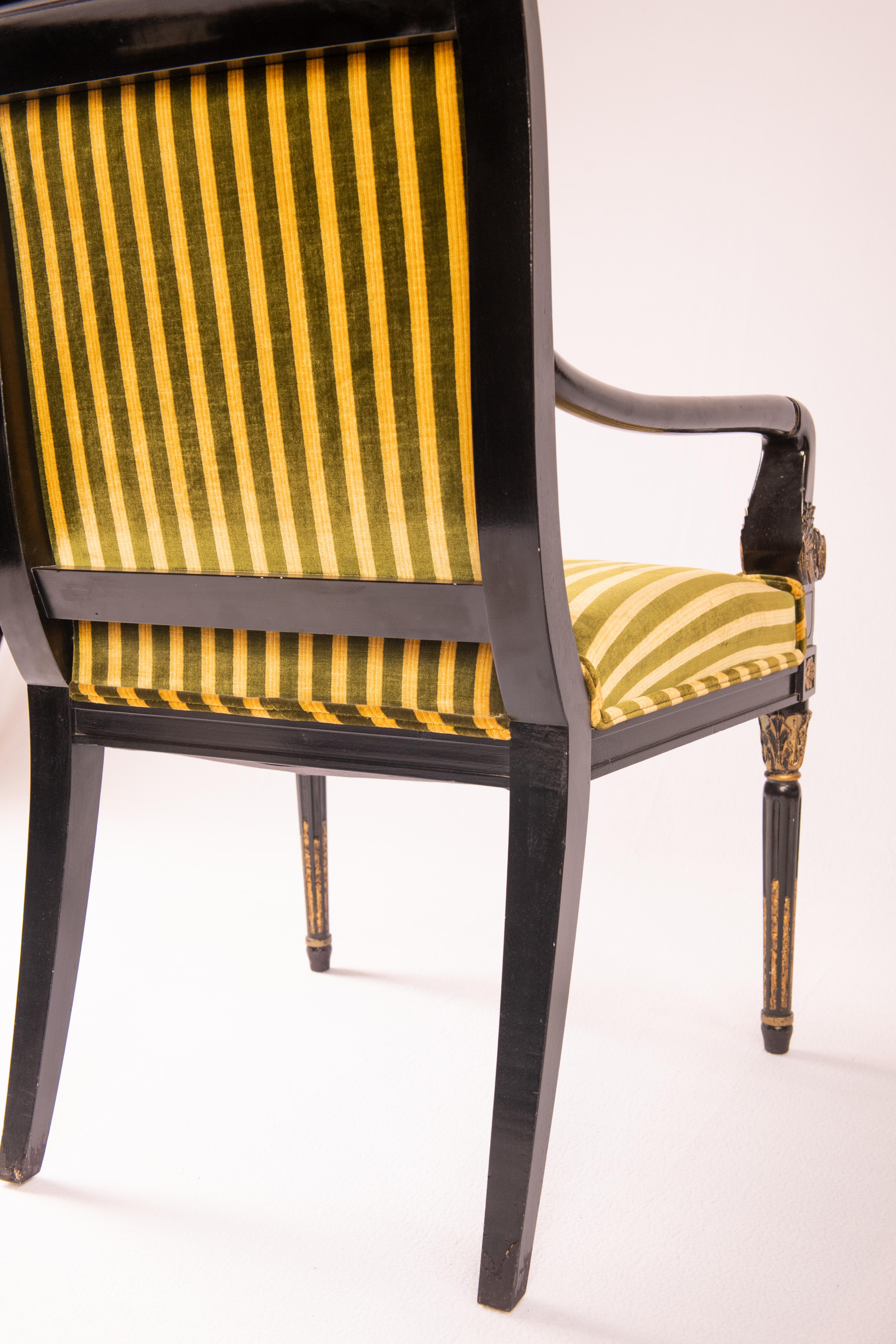 Beautiful ebonized and parcel gilded Regency-style armchair.  The stripe velvet upholstery is newer.  This chair displays a finely carved and gilded tapered legs and arms with a simple ebonized rail with small florets on the side.  The florets are