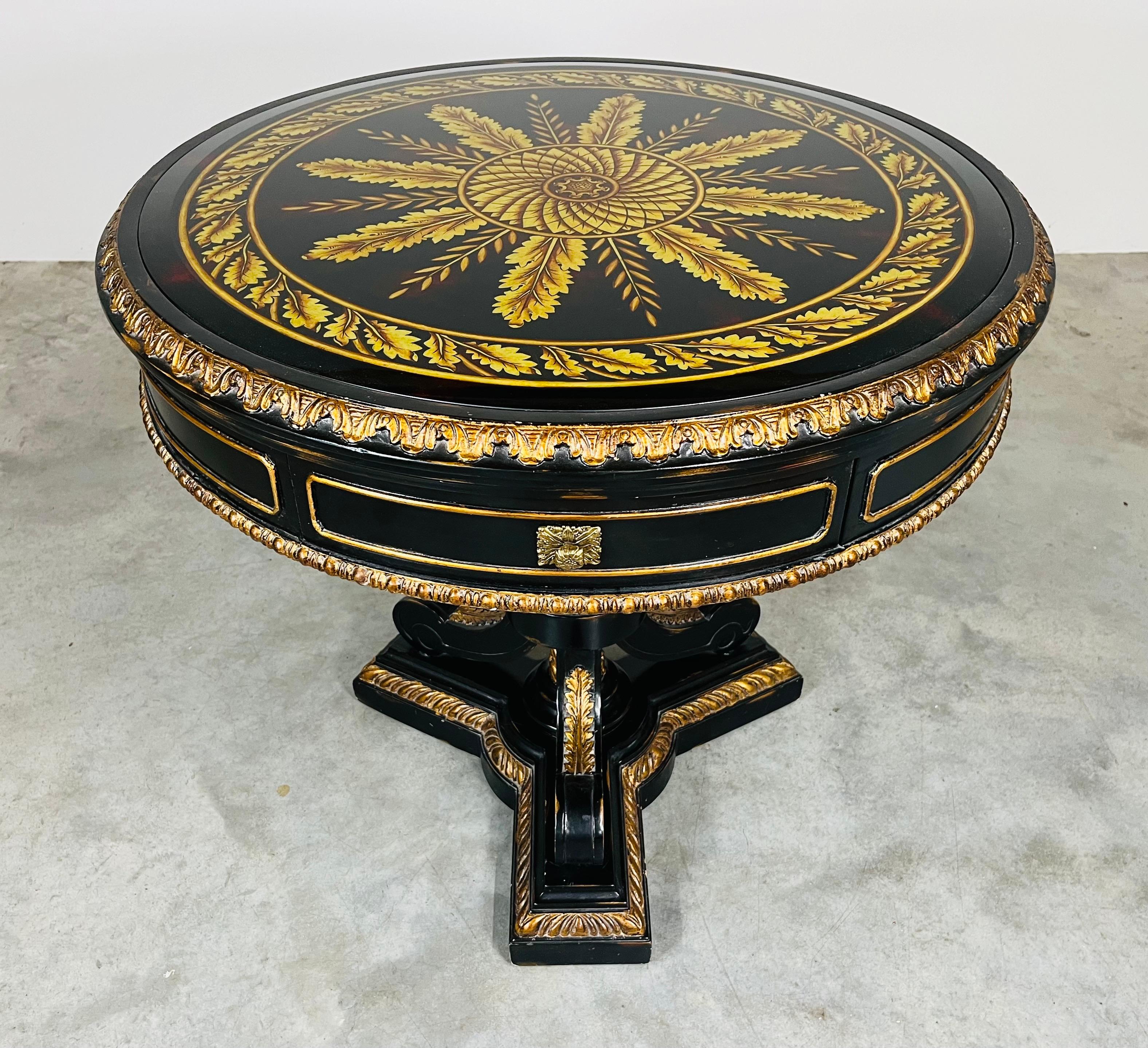 Maitland Smith Empire style pedestal base single drawer foyer or center table with Eglomise glass top. Highly detailed craftsmanship having hand carved base black lacquered with gold finish details. 21st century.
30
