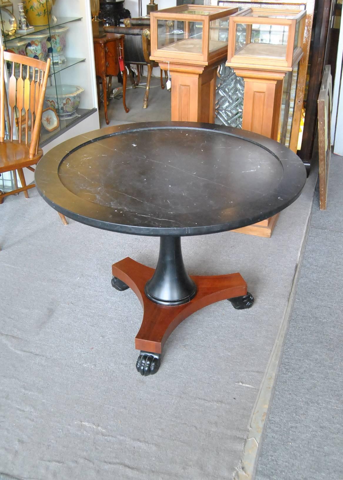 An impressive Empire style round centre table by Ralph Lauren. It features a black marble top and a mahogany base with carved claw feet. This comes with an adapter to add 1 1/2