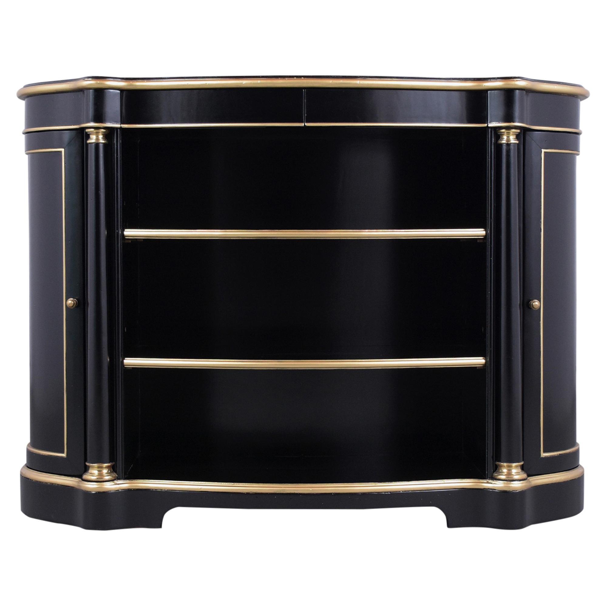 A remarkable empire-style bookshelf crafted out of mahogany wood that has been refinished in a newly ebonized color with elegant gilded molded accents and lacquer finish. This cabinet has been professionally restored comes with two center columns