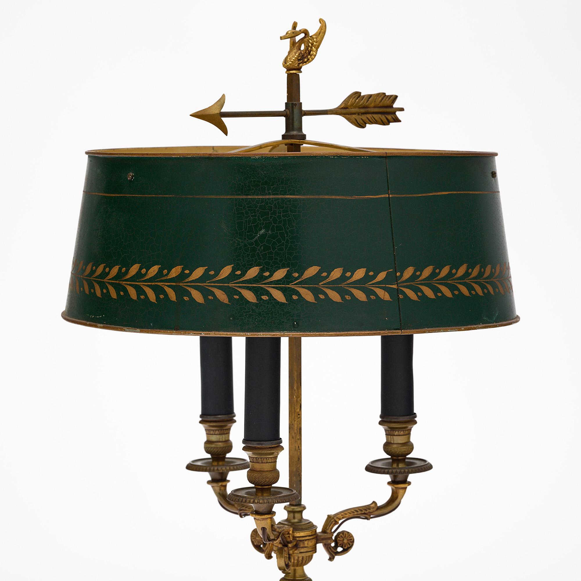 Bouillote lamp, French, in the Empire style. This French antique lamp features three candelabras and a green painted tole shade with a gold leaf frieze. On its top sits a decorative finial representing a swan on an arrow. It has been newly wired to