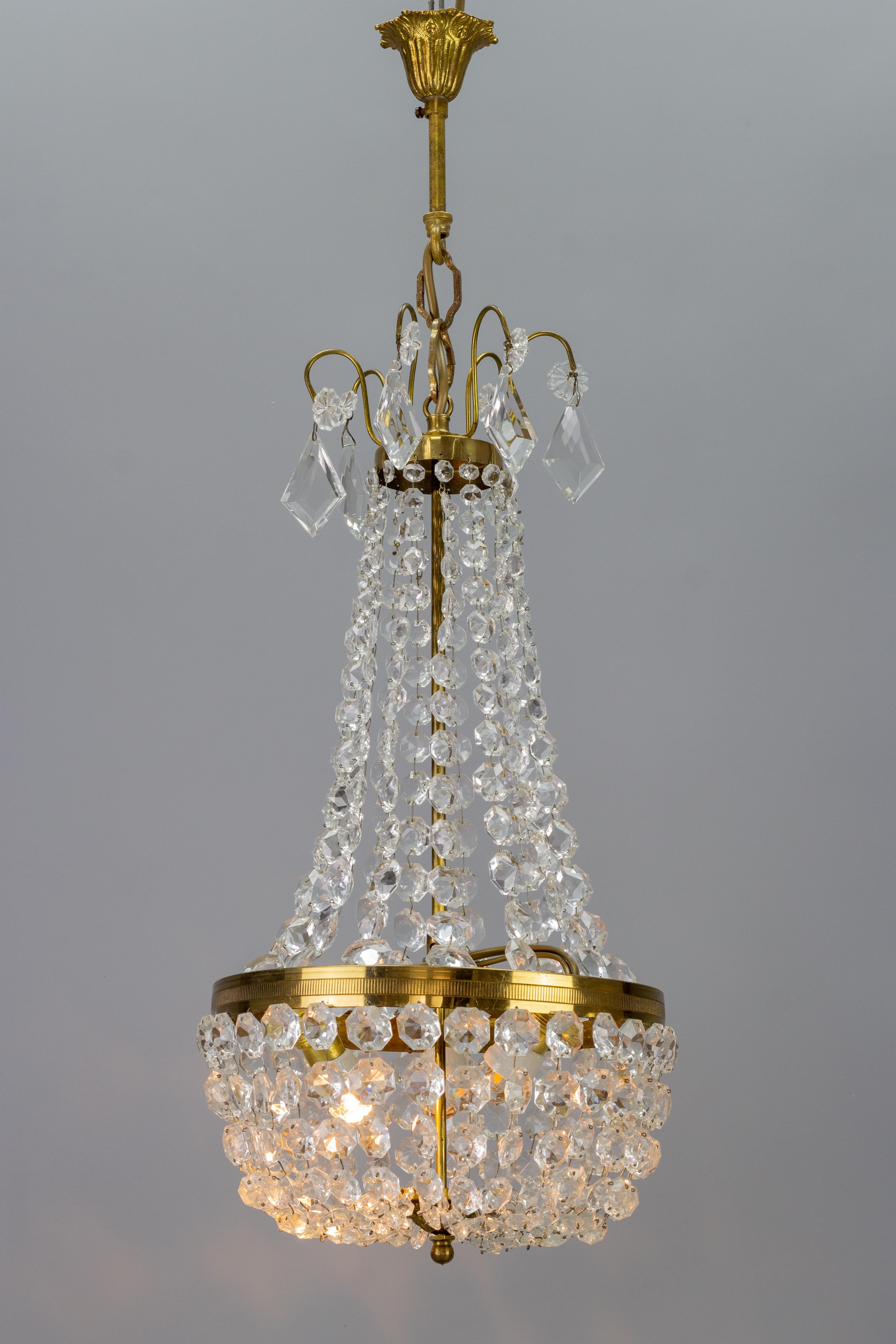 Adorable French Empire-style crystal glass and brass chandelier from the 1950s. This lovely piece has a brass and metal frame hung with chains of crystal glass beads forming a basket and reflecting the light beautifully. Adorned with hanging crystal