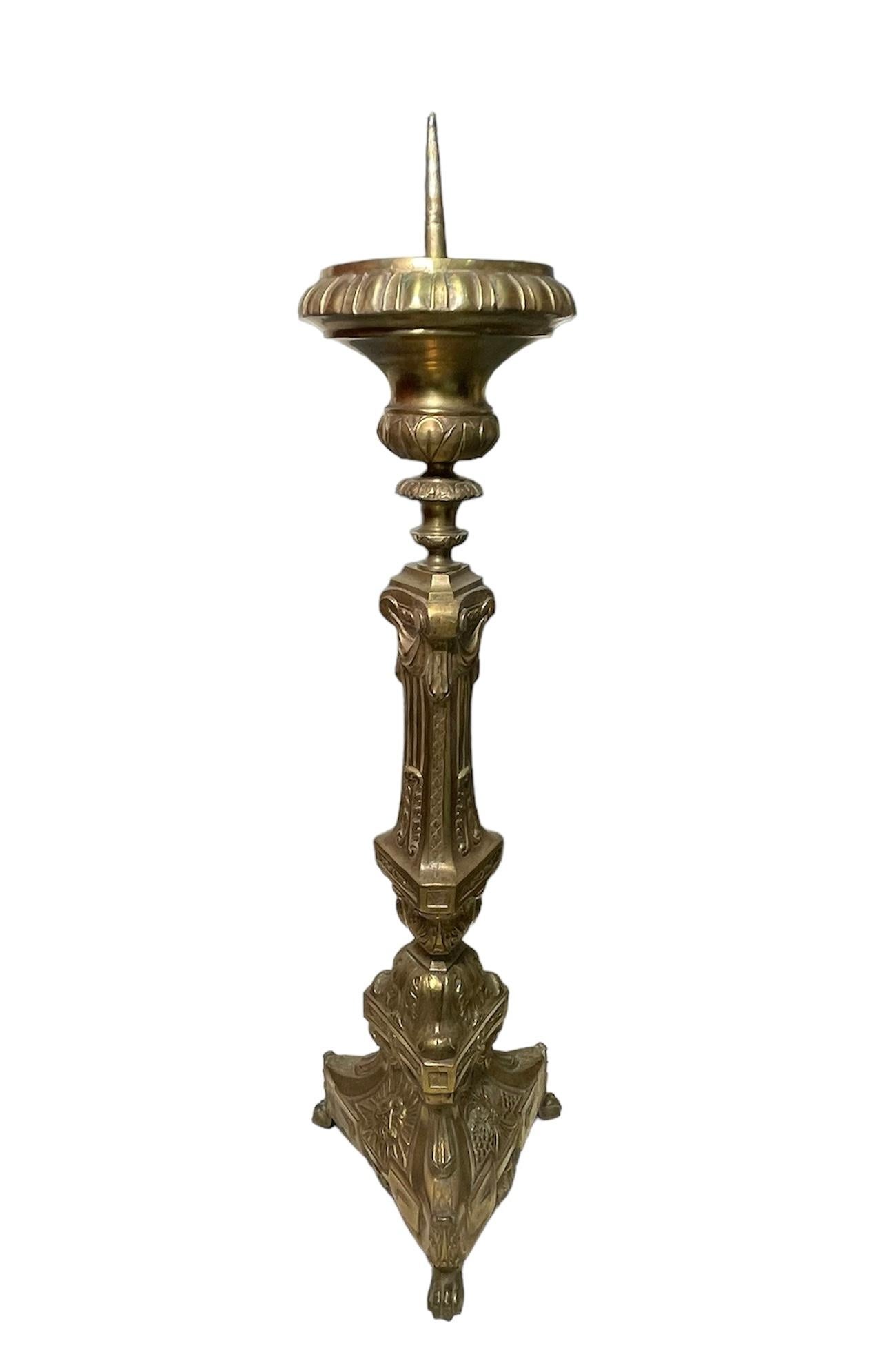 This an Empire Style Bronze Candle holder or Candlestick. It depicts a gilt bronze candle holder decorated with a high relief of wheat branches, grapes vines, acanthus leaves, bay leaves and swags. The candle holder is supported by three lion paws.