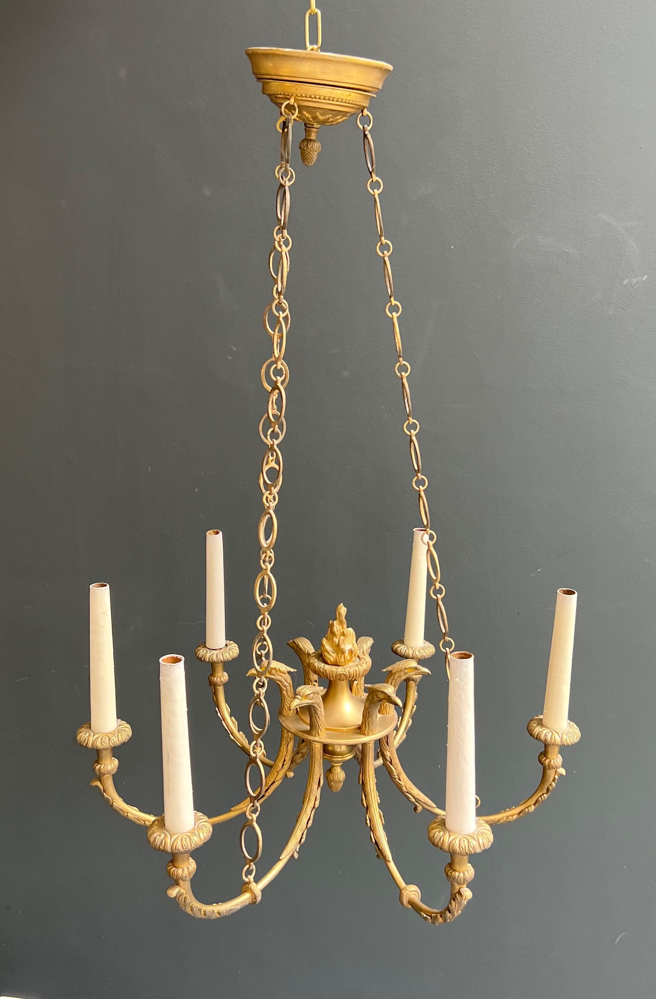 Araña de bronce de estilo imperio con cabezas de águila real y llama. Esta lámpara de araña Imperio en venta