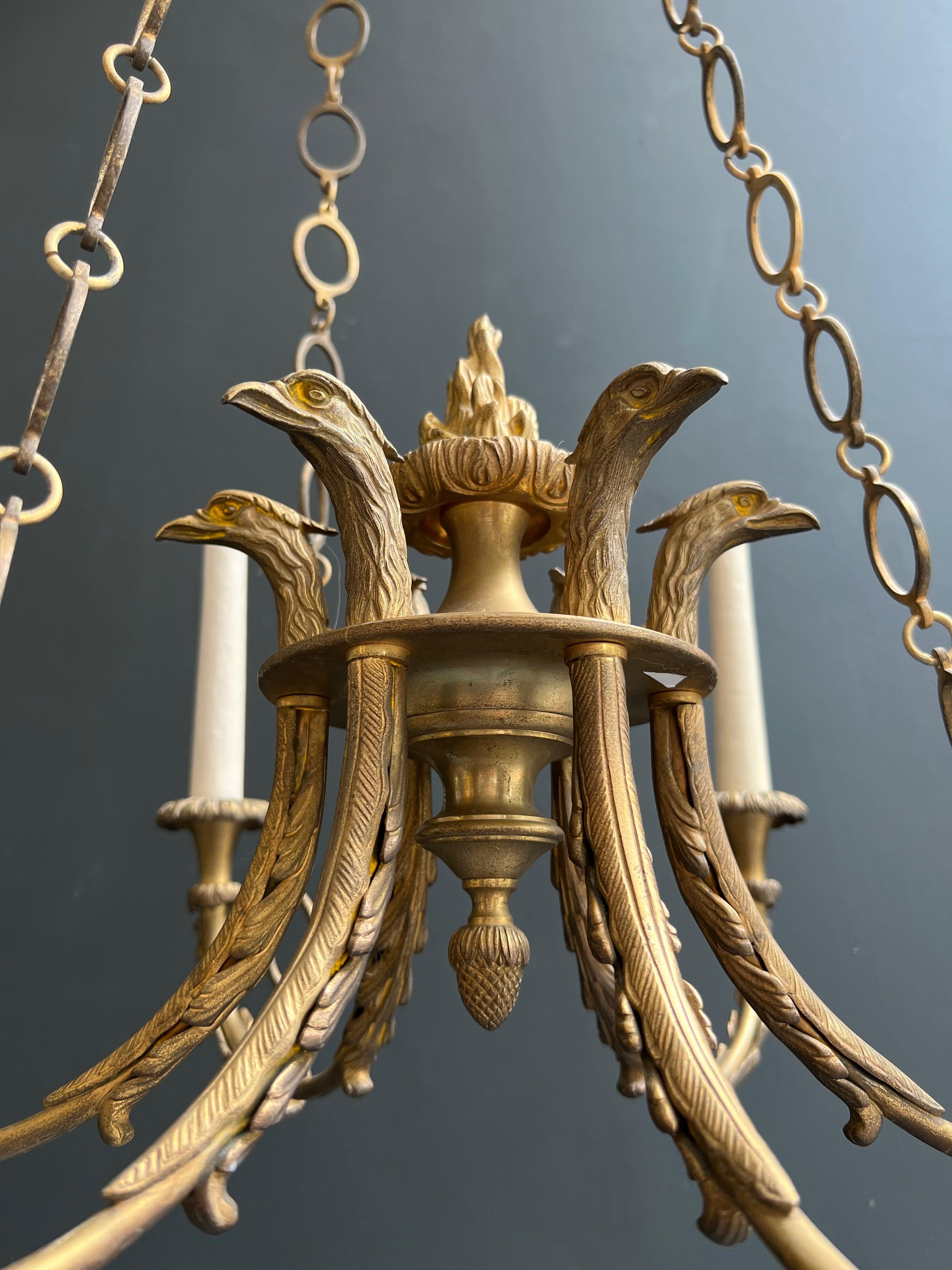 Araña de bronce de estilo imperio con cabezas de águila real y llama. Esta lámpara de araña principios del siglo XX en venta