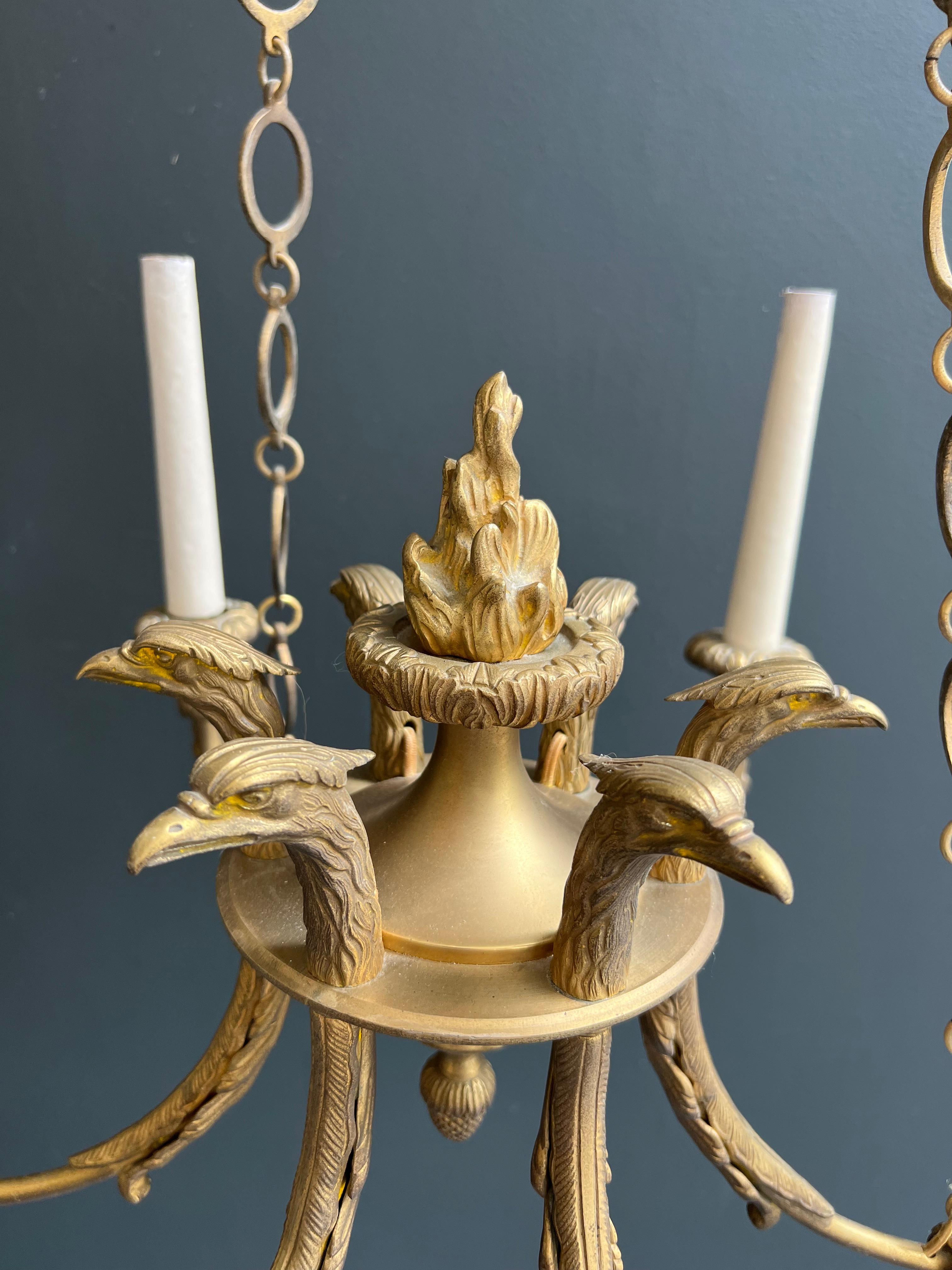 Araña de bronce de estilo imperio con cabezas de águila real y llama. Esta lámpara de araña en venta 1