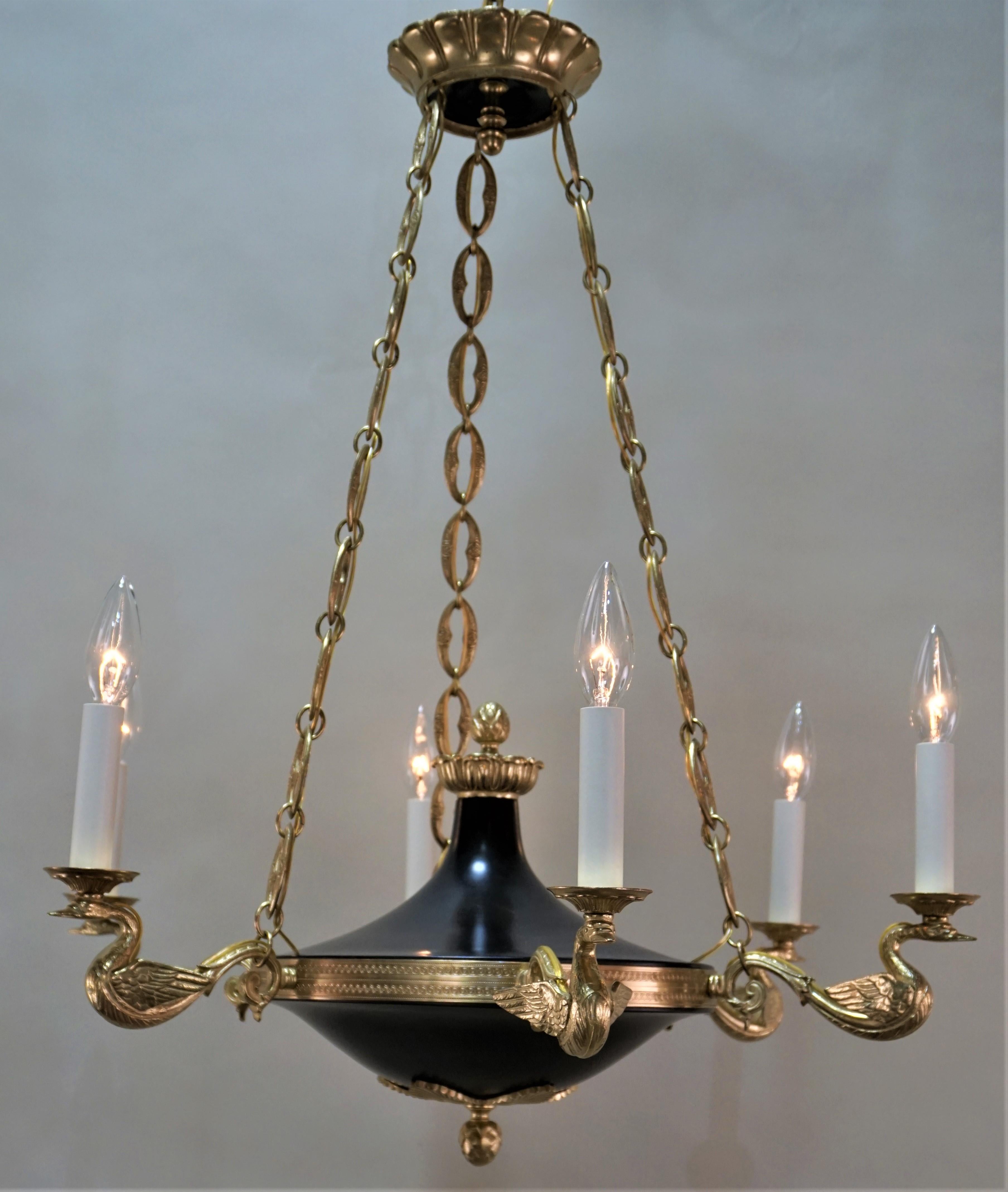 This Empire style chandelier is crafted from solid cast bronze in France, circa 1930s. This chandelier has six swan arms and black lacquer centre body. This chandelier is designed for six candelabra bulbs.