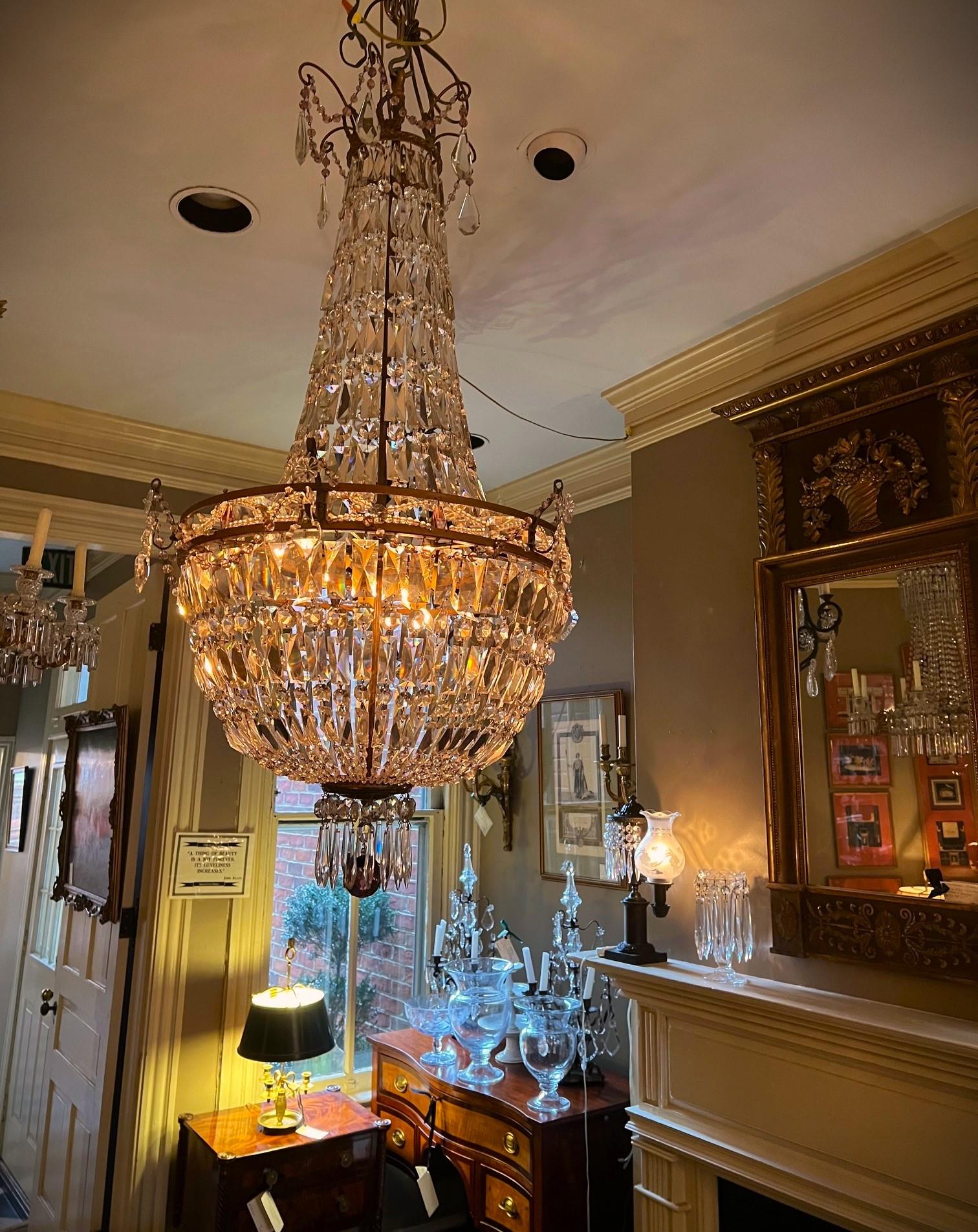 This armless tent-and-basket chandelier was hand crafted in the Empire style in Paris in the early days of electrified light fixtures. Inside the bronze frame, hidden by the tent of crystal buttons & baguette prisms, are 6 lights attached to a