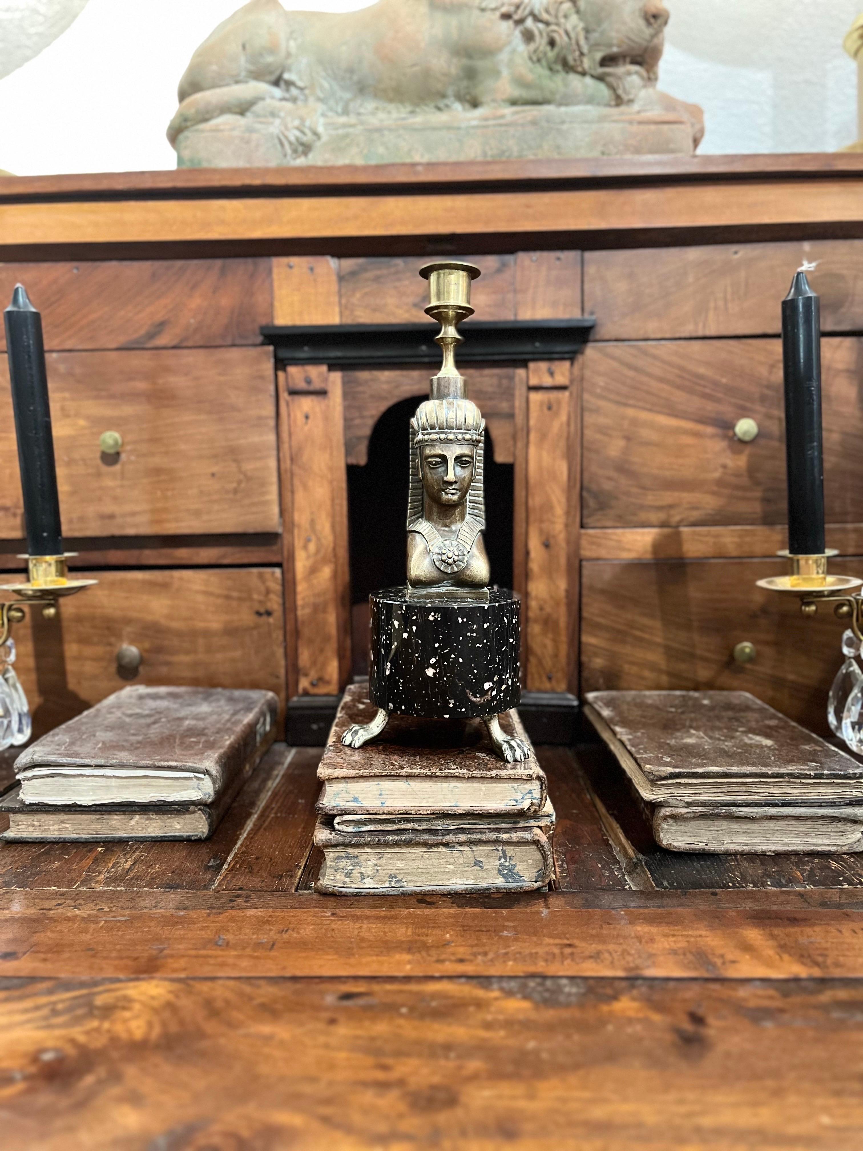 Empire style candlestick, with a cylindrical porphyry base that rests on three bronze claws, the base is the support of the bronze figure of a sphinx or Egyptian character.