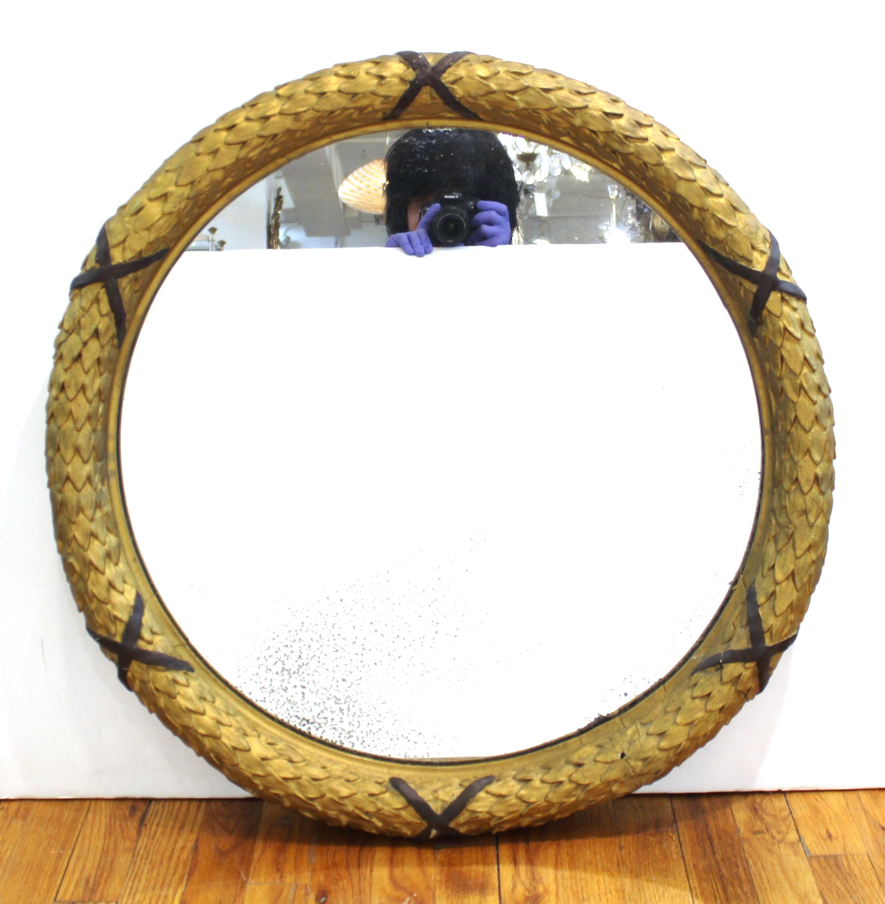 Empire style antique carved giltwood round wall mirror. The piece has a gilt wreath carved border. In great antique condition with age-appropriate wear and use.