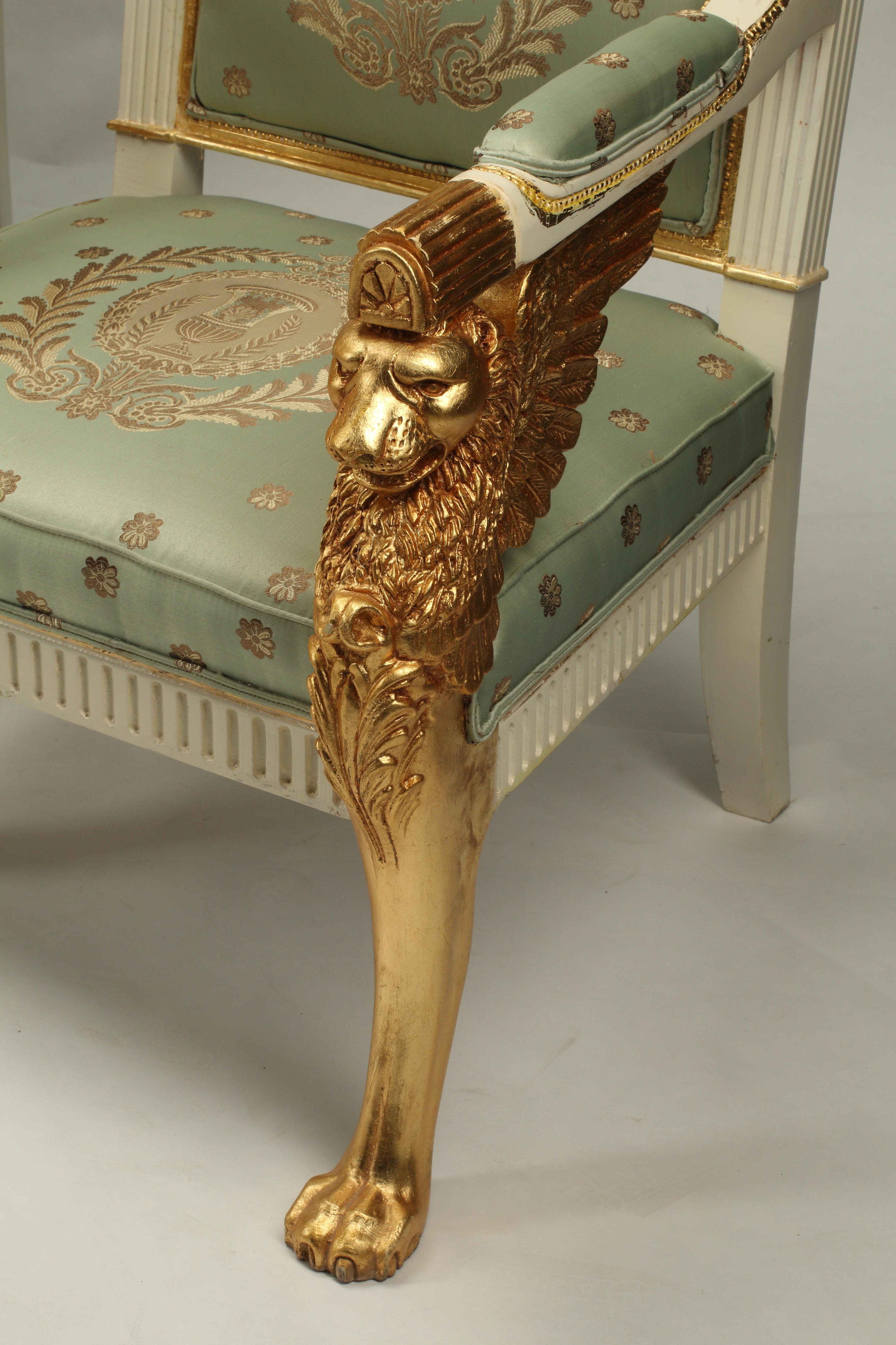 Questo squisito completo di poltrona e divanetto in stile Impero, intagliato a mano e realizzato in un'impressionante combinazione di legno dorato e dipinto color crema, esemplifica la grandezza dell'epoca napoleonica. La suite è caratterizzata da