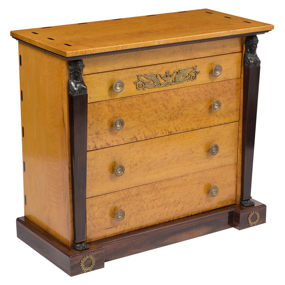 A fabulous 1950s French Empire-style chest or dresser that is made from solid wood finished in a Flemish maple color, with prism designs on the top and sides. There are two columns on the front with caryatid details at the base and capital that are