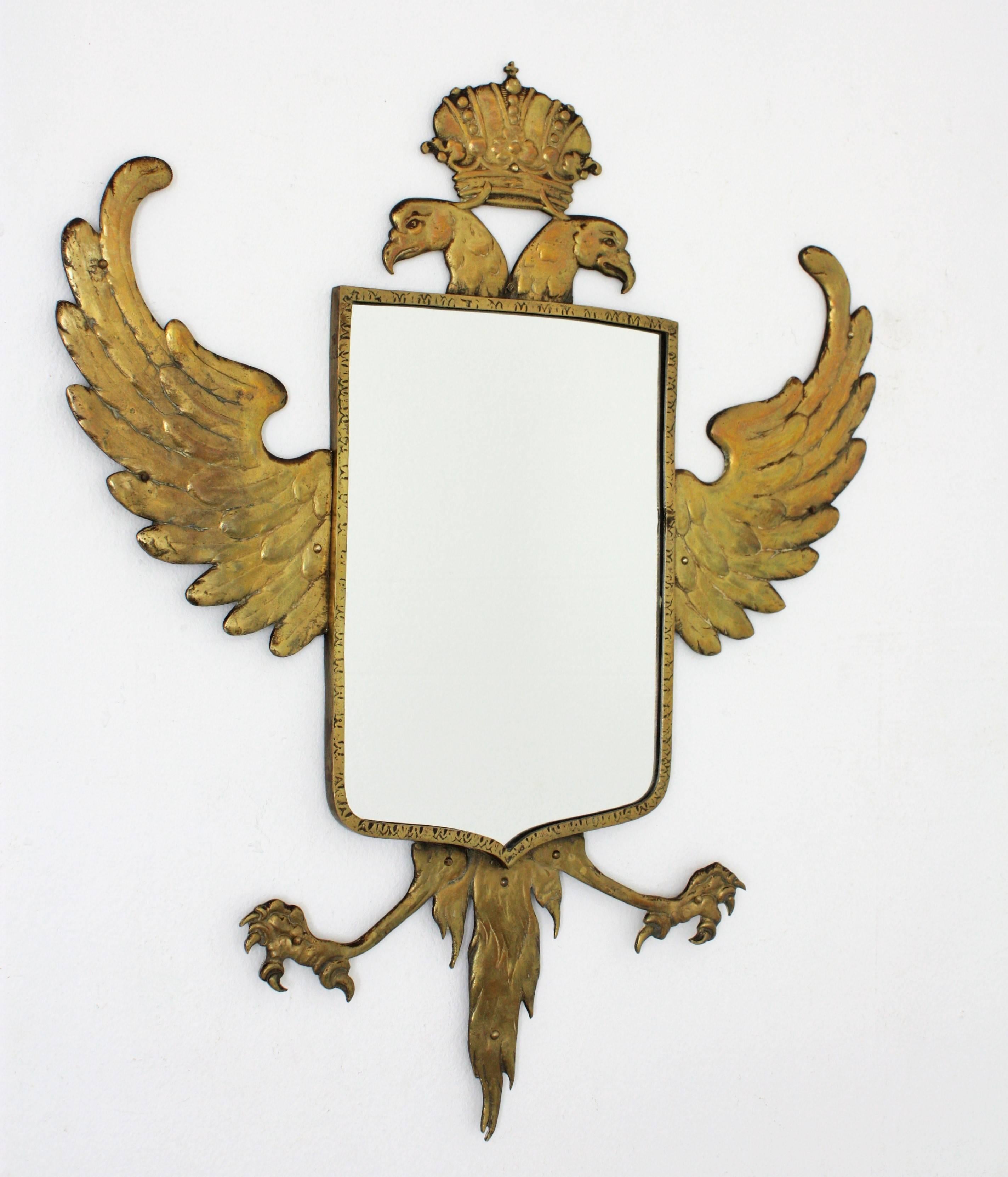 Spectacular bronze wall mirror with a crowned double headed eagle surrounding a coat of arms shaped glass. A double headed eagle with wide open wings and a crown finished by a small cross. The bronze work is full of realistic details to make this