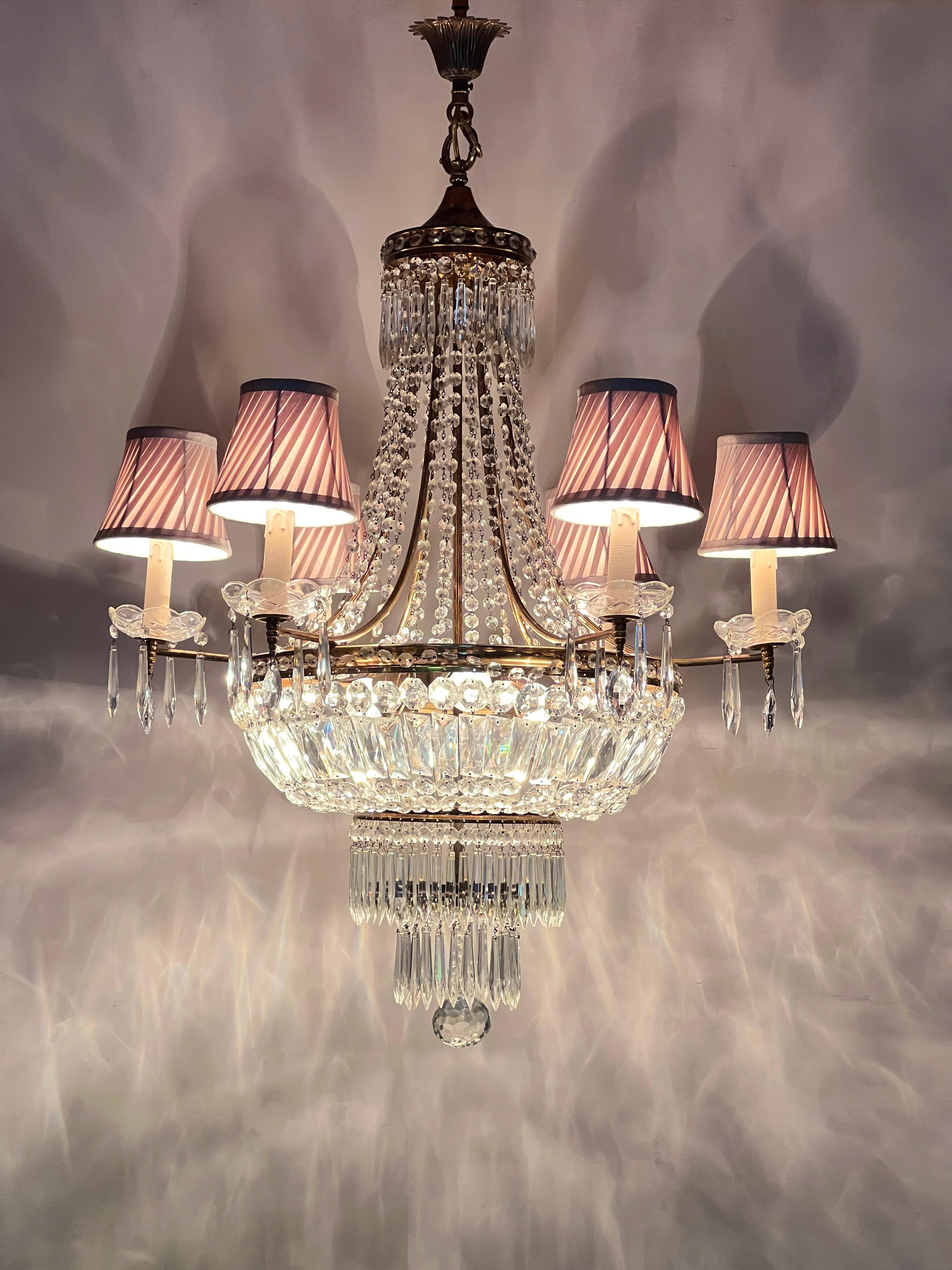 An exquisite Empire Style Crystal and Brass Tent and Bag Chandelier. This beautiful chandelier features a brass ceiling rose with a charming acanthus leaf design and a tent-top brass canopy adorned with crystal facet-cut icicle drops. The impressive