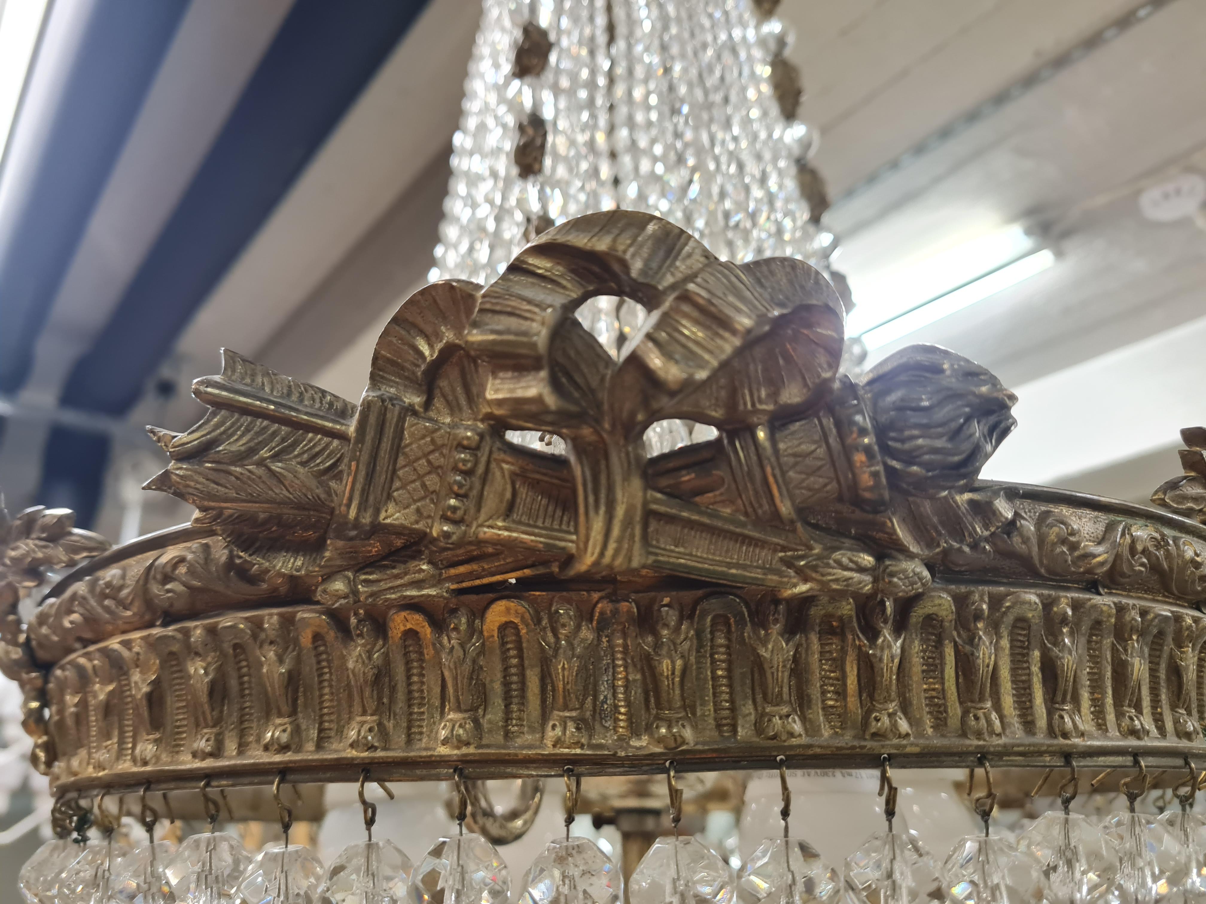 Uno squisito esempio di lampadario in cristallo a goccia, probabilmente in stile Impero francese o revival, con la corona d'alloro, la fiamma e le frecce in bronzo. La lampada risale alla fine del 1800 o all'inizio del XX secolo ed è in ottime
