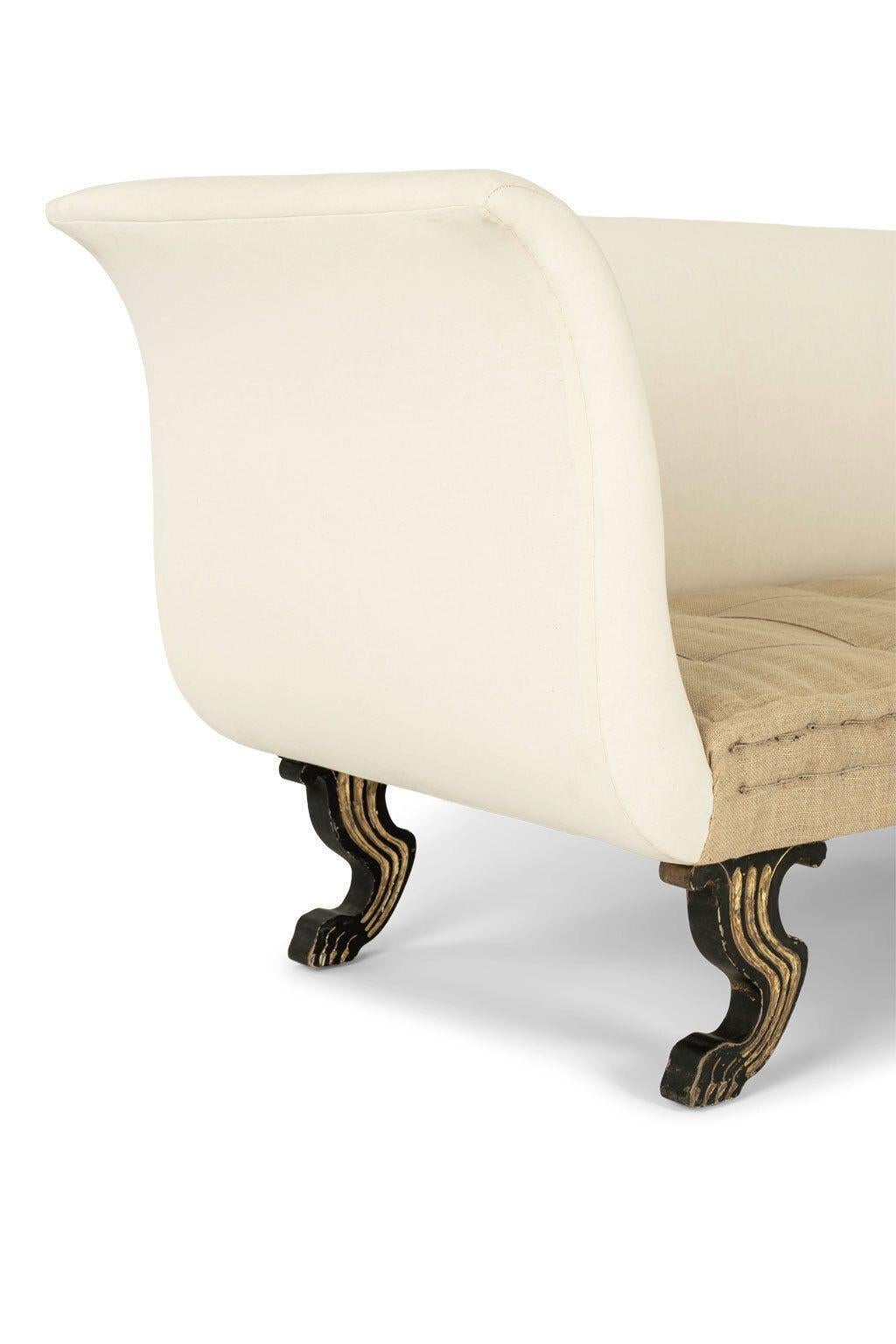 Empire style curved-arm daybed, or sofa, raised upon ebonized silhouette paw feet with gilt decoration. Newly upholstered in off-white muslin and washed burlap. Large proportions with deep seat.