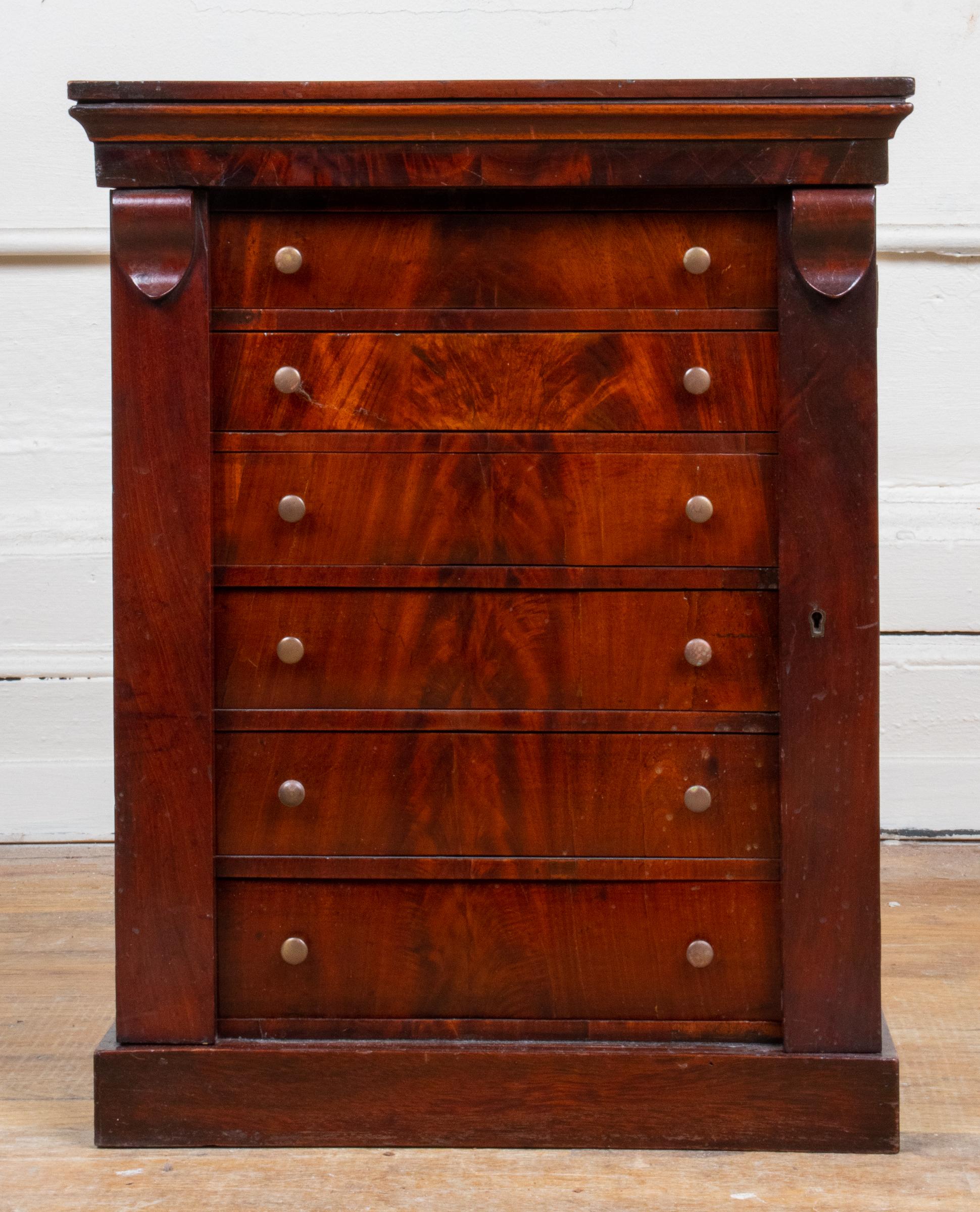 Empire style diminutive flame mahogany chest, with six drawers flanked by two shutter flaps. In great antique condition with age-appropriate wear. Measures: 19.75” H x 15.5” W x 10.75” D.