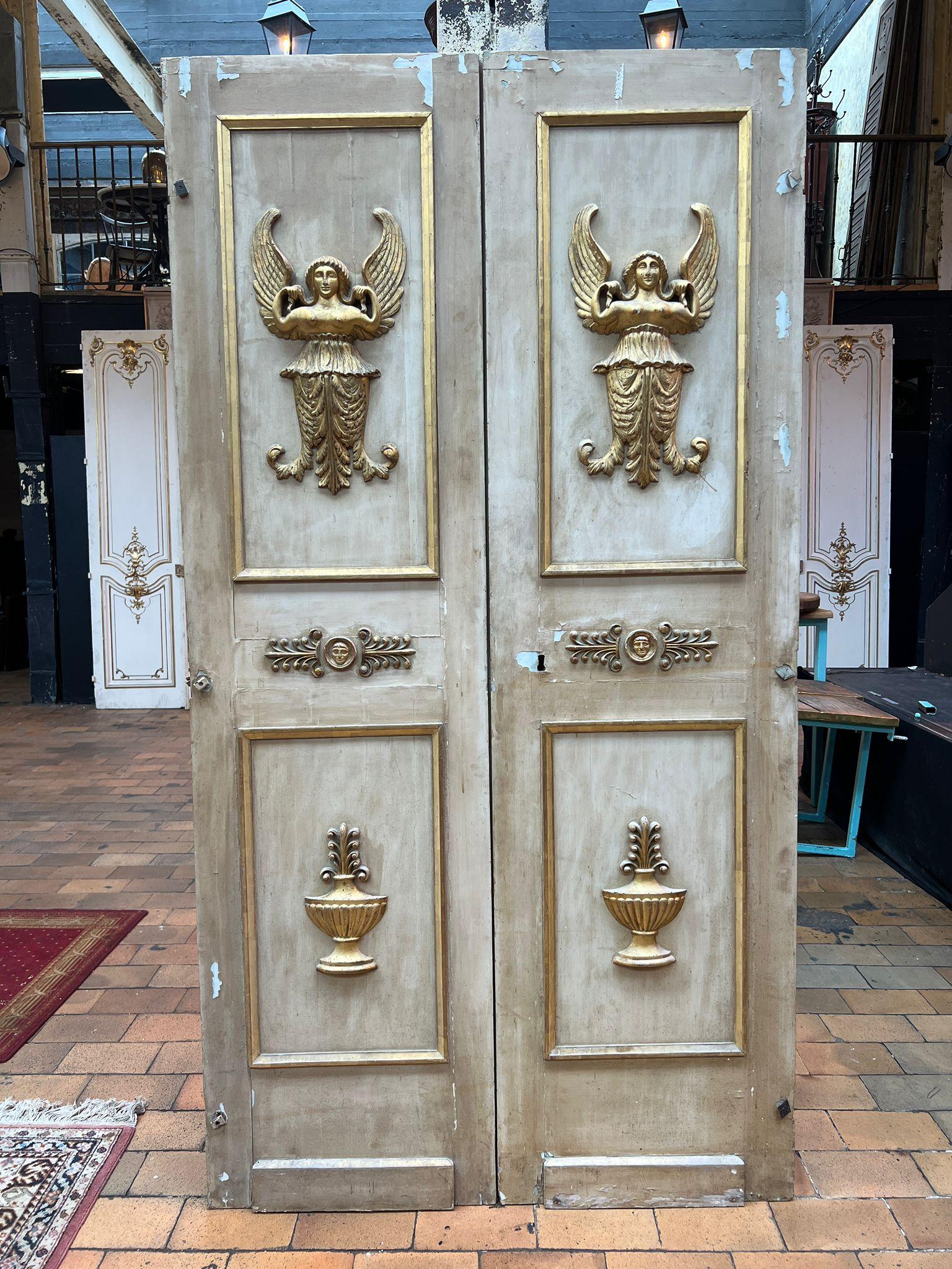 Ein auffallendes Paar doppelter Schranktüren im Empire-Stil aus dem 19. Jahrhundert, die sich durch neoklassische Eleganz und raffinierte Verzierungen auszeichnen. Diese antiken Holztüren sind mit kunstvoll geschnitzten Applikationen versehen,