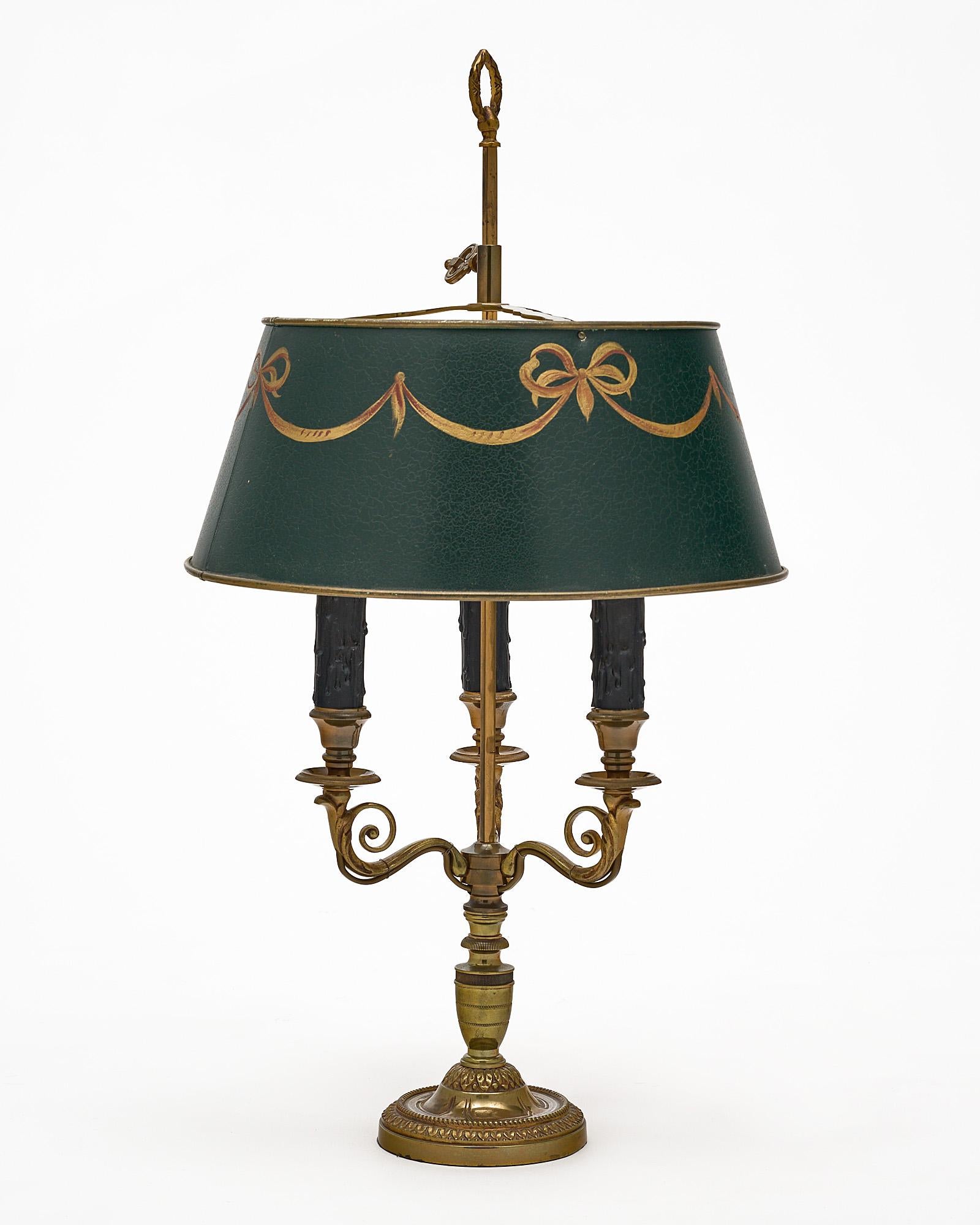 Bouillotte lamp; French; in the French Empire style. This piece has a base made of finely cast bronze featuring three arms. There is a beautiful hand painted and gold leafed adjustable green shade. It has been newly wired to fit US standards. The