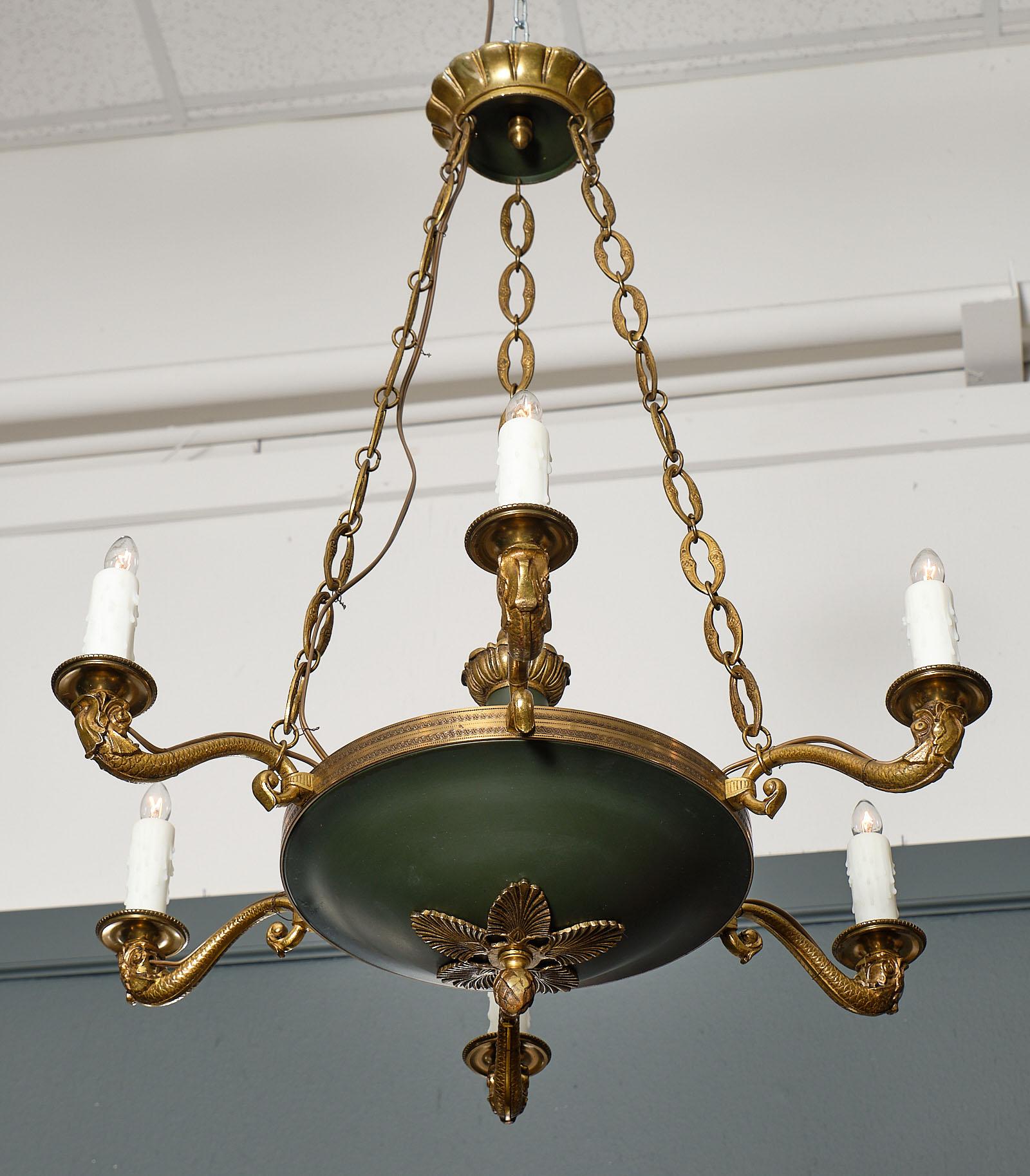 French Empire style bronze chandelier with six candelabra branches and featuring a dark green lacquered body. The arms are beautifully stylized and cast bronze Roman dolphins holding the bobeche. The chains and canopy are all original. This piece