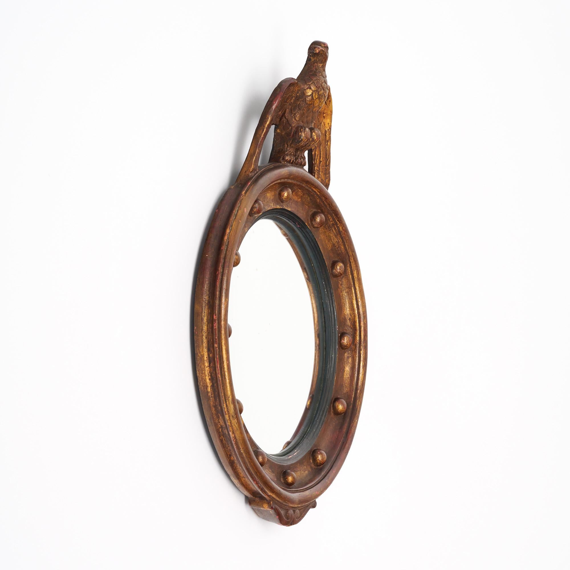 Specchio francese in stile Impero. Questo pezzo è realizzato in legno massiccio e rifinito con foglia d'oro e una patina originale. In cima allo specchio circolare si trova un'aquila, simbolo dello stile Impero. Questo pezzo è in ottime condizioni