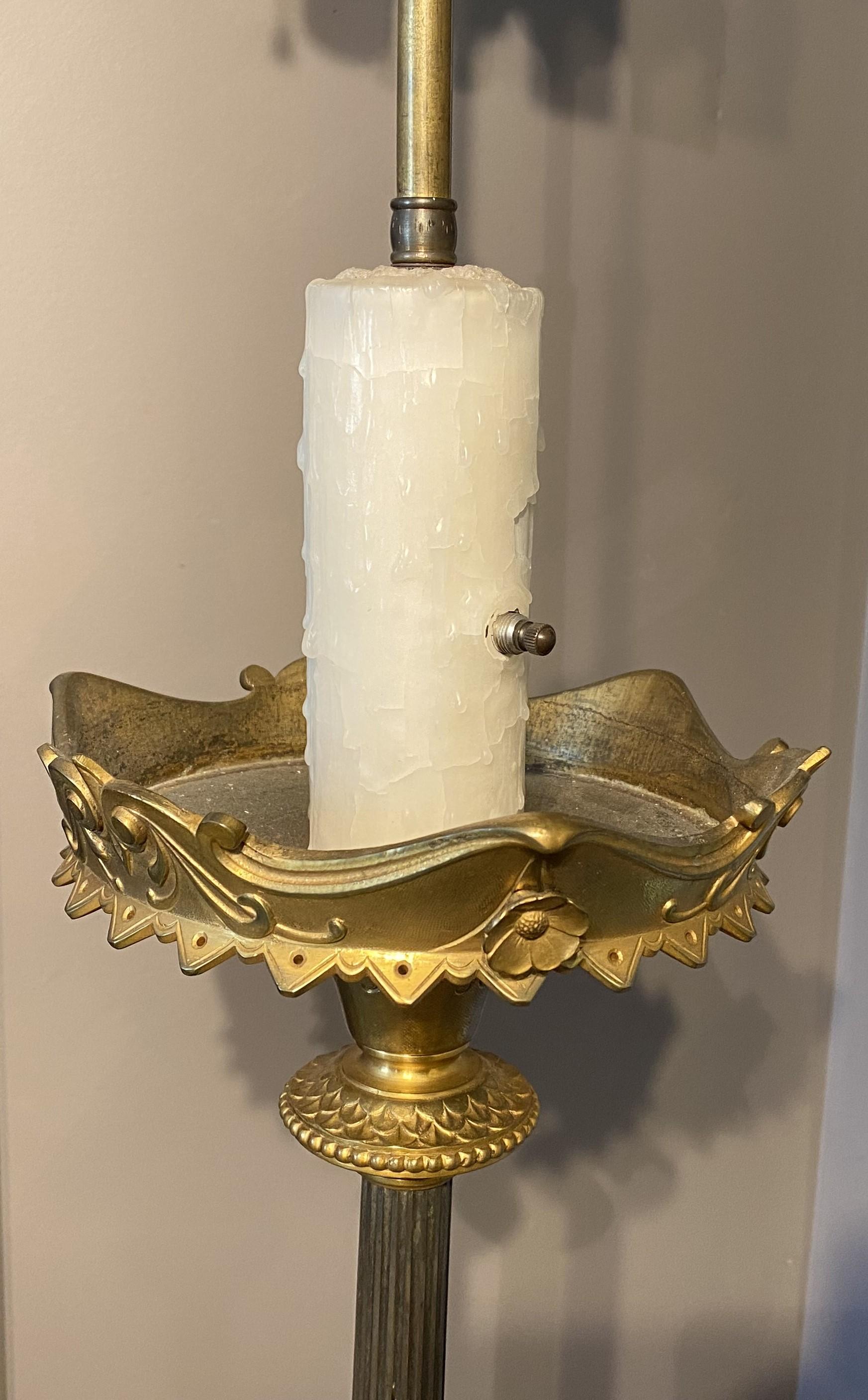 Un bel exemple de lampadaire torchère lourd de style Empire en bronze patiné et doré à deux lumières, avec une base ébonisée.  L'étalon est décoré de feuillages et d'un faux interrupteur central, accentué par une grande bobèche en bronze et soutenu