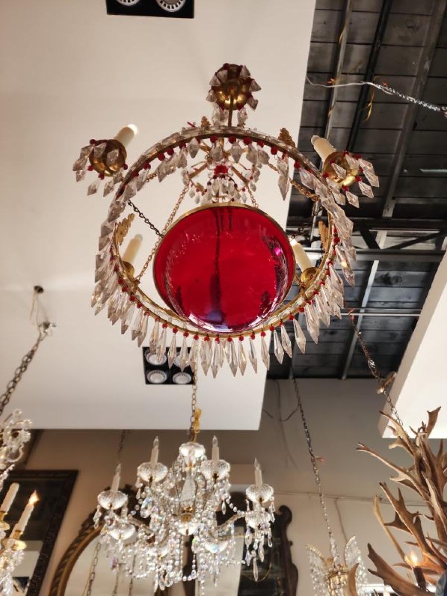 This listing features an Empire style Gilt-brass and cut-glass chandelier that houses five candlestick lights and is approximately 18
